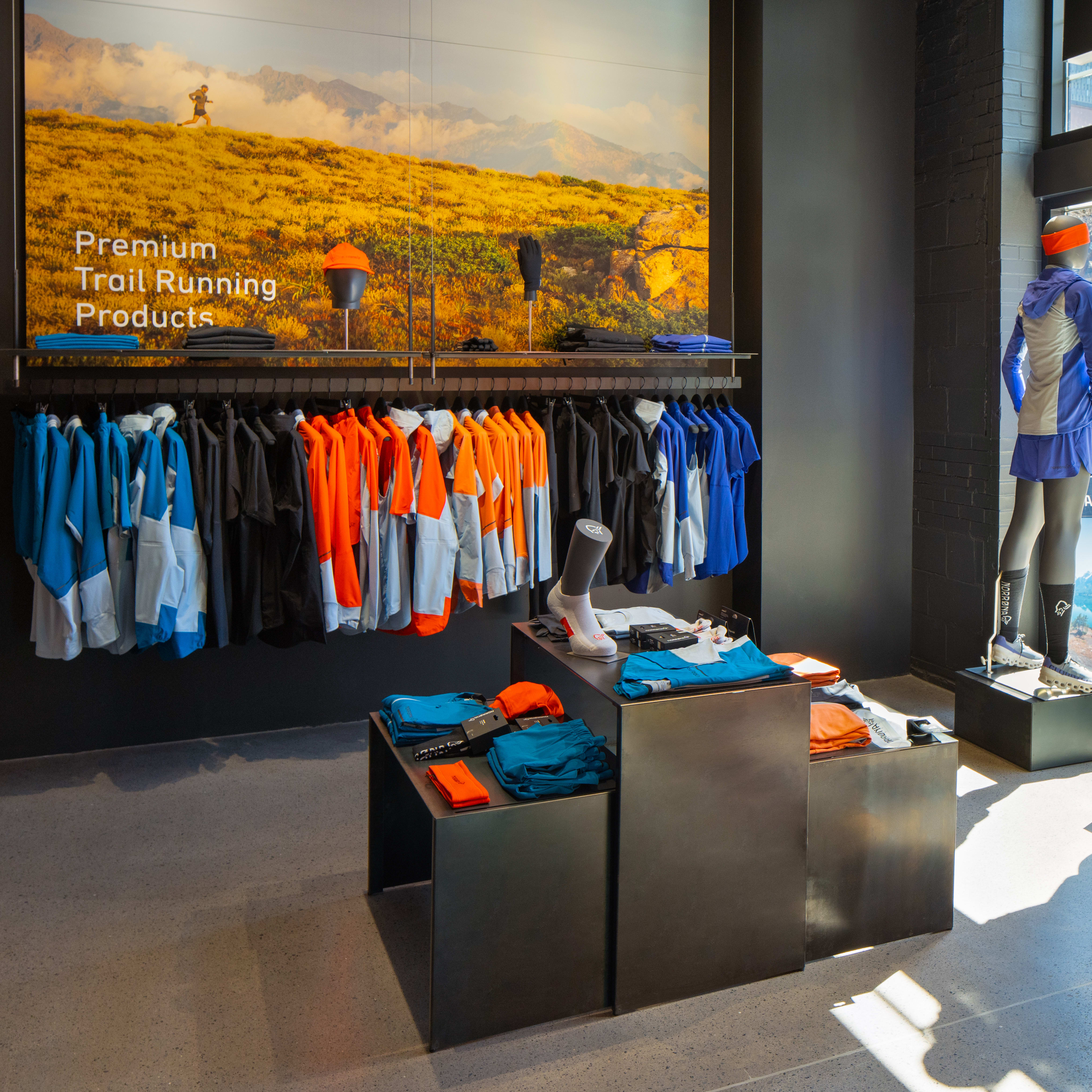 Three mannequins wearing Norrøna trail running gear stand in a store window. The mannequins are displaying a variety of Norrøna products.  
