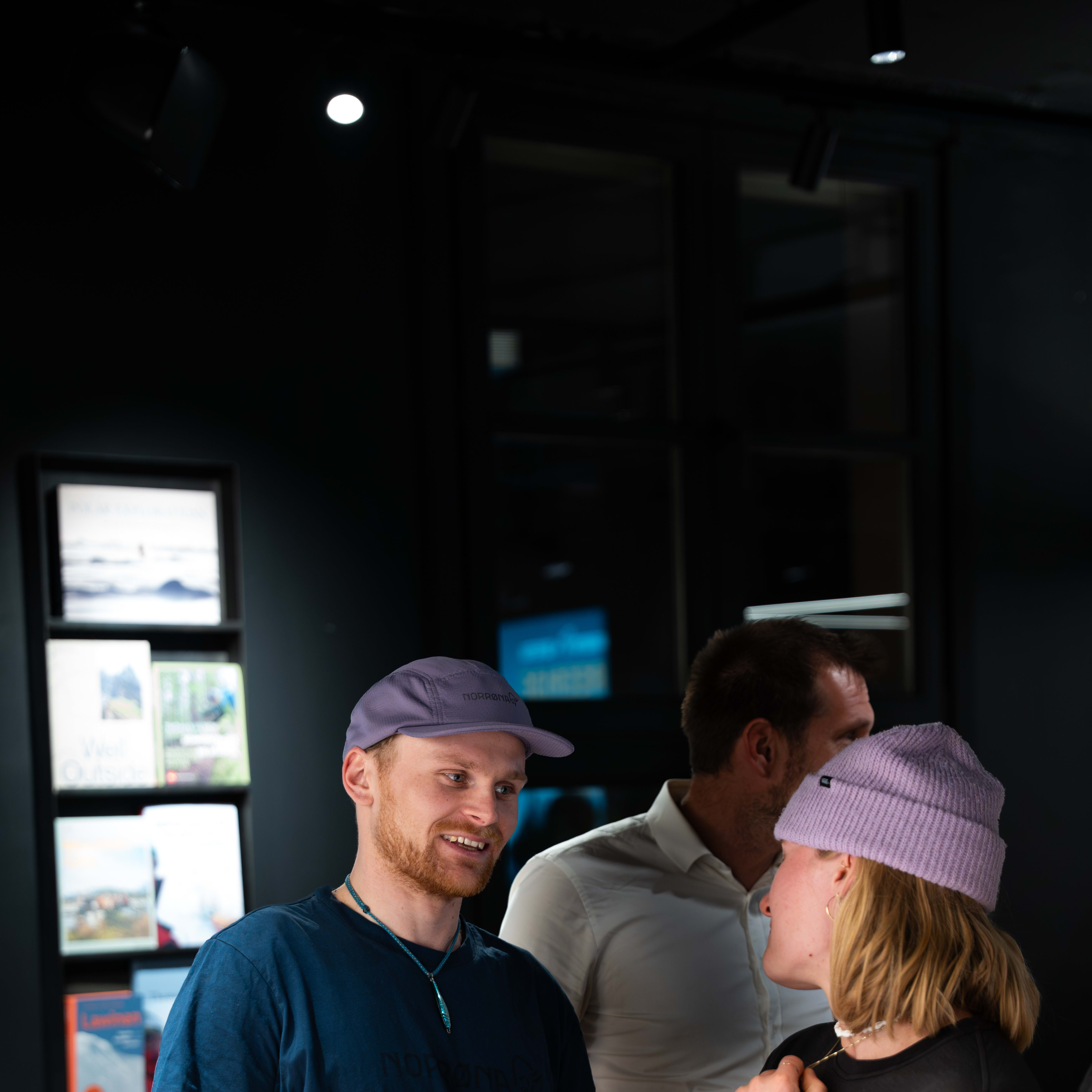 Presenters in Norrøna clothing stand by a screen showing 'ADHD' before a seated audience in a dark venue.