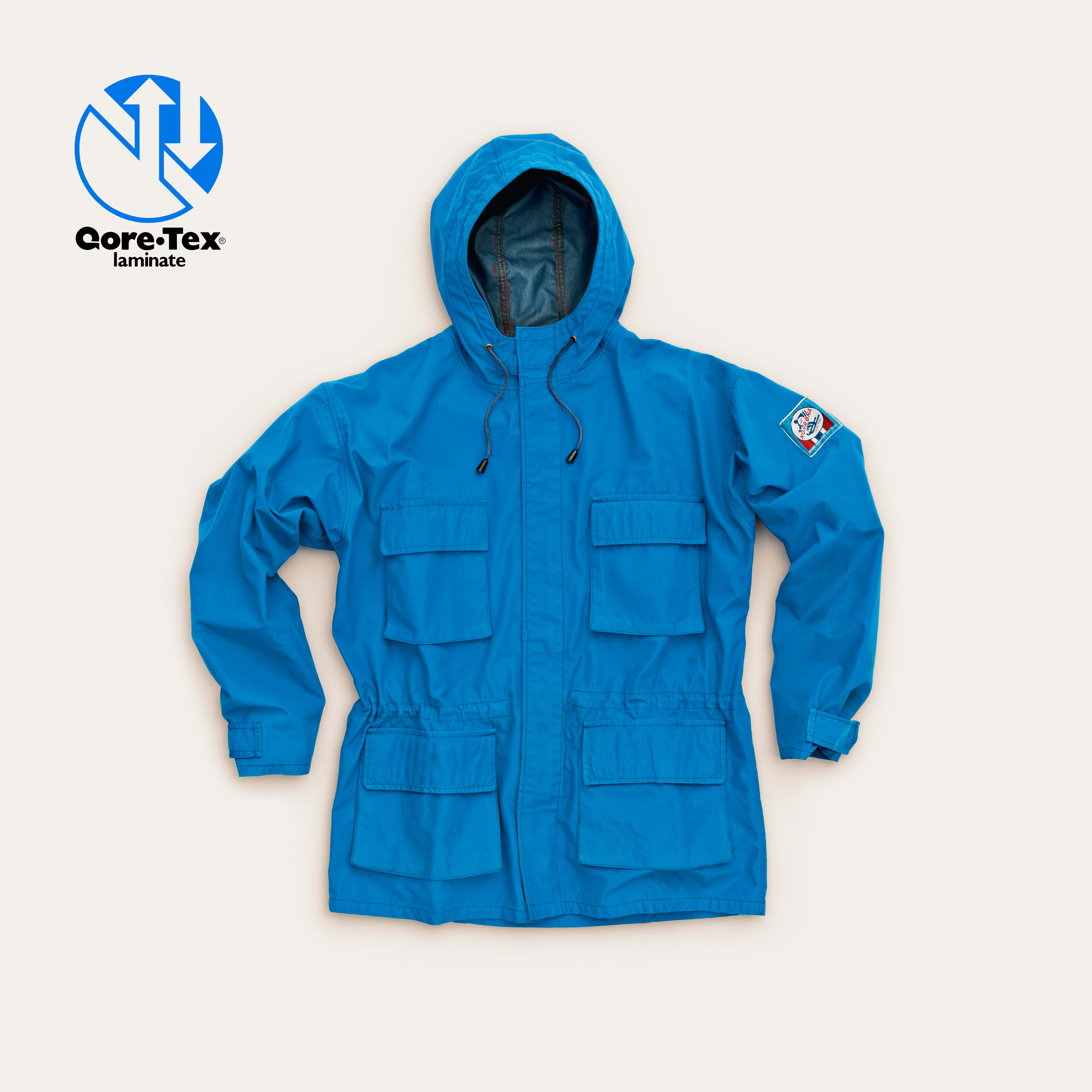 A bright blue Norrøna Gore-Tex hooded jacket with multiple pockets, displayed on a pale background.