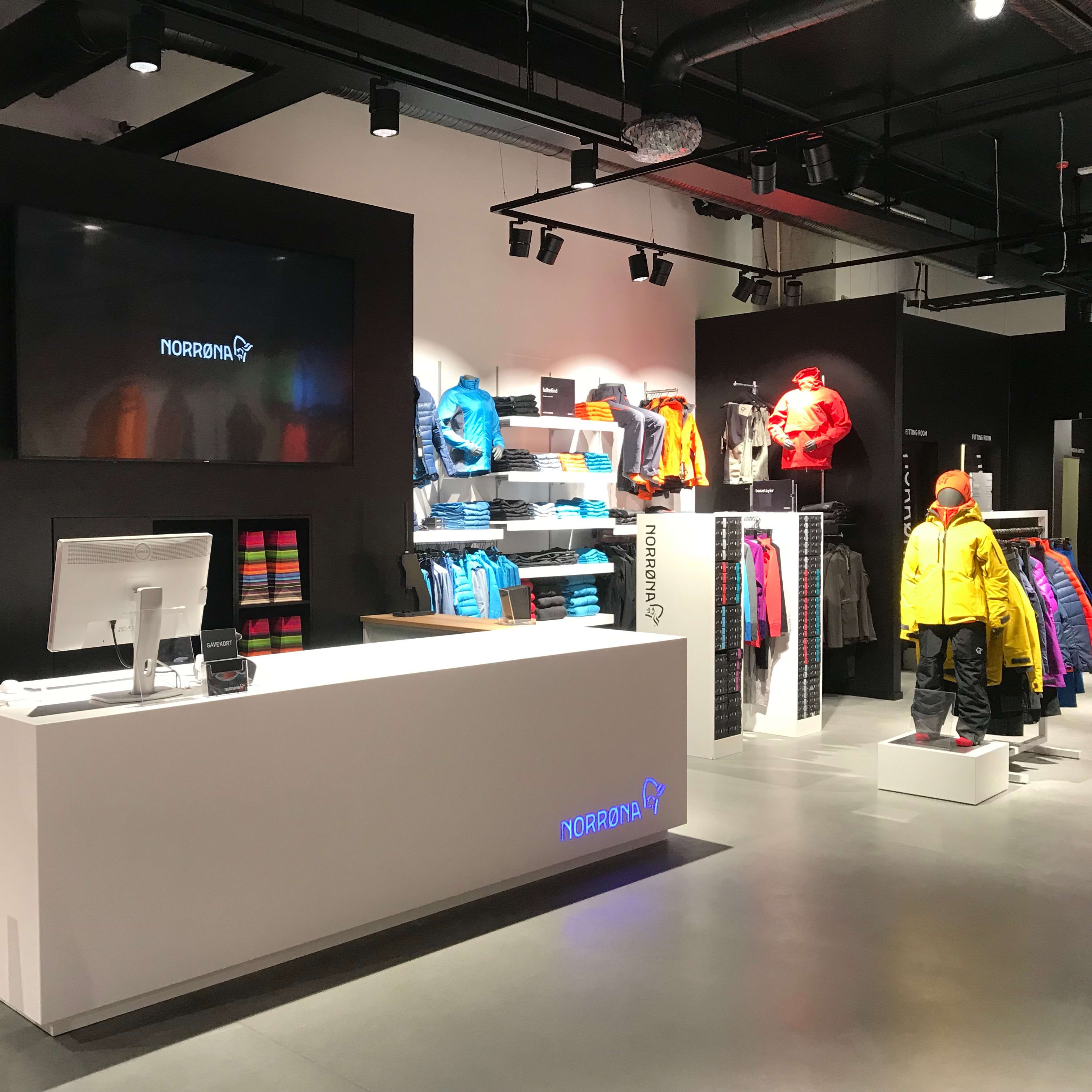 Interior of a Norrøna retail store featuring a white checkout counter and colorful Norrøna clothing displays.