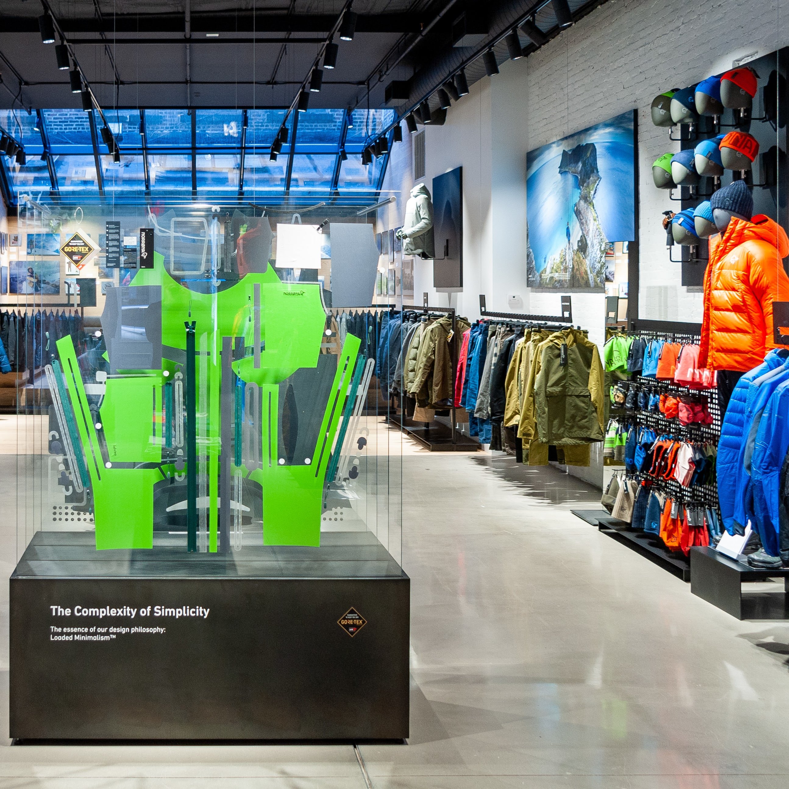 A Norrøna clothing store interior with a green display case. The case is a schematic of a garment with "Loaded Minimalism" text below.
