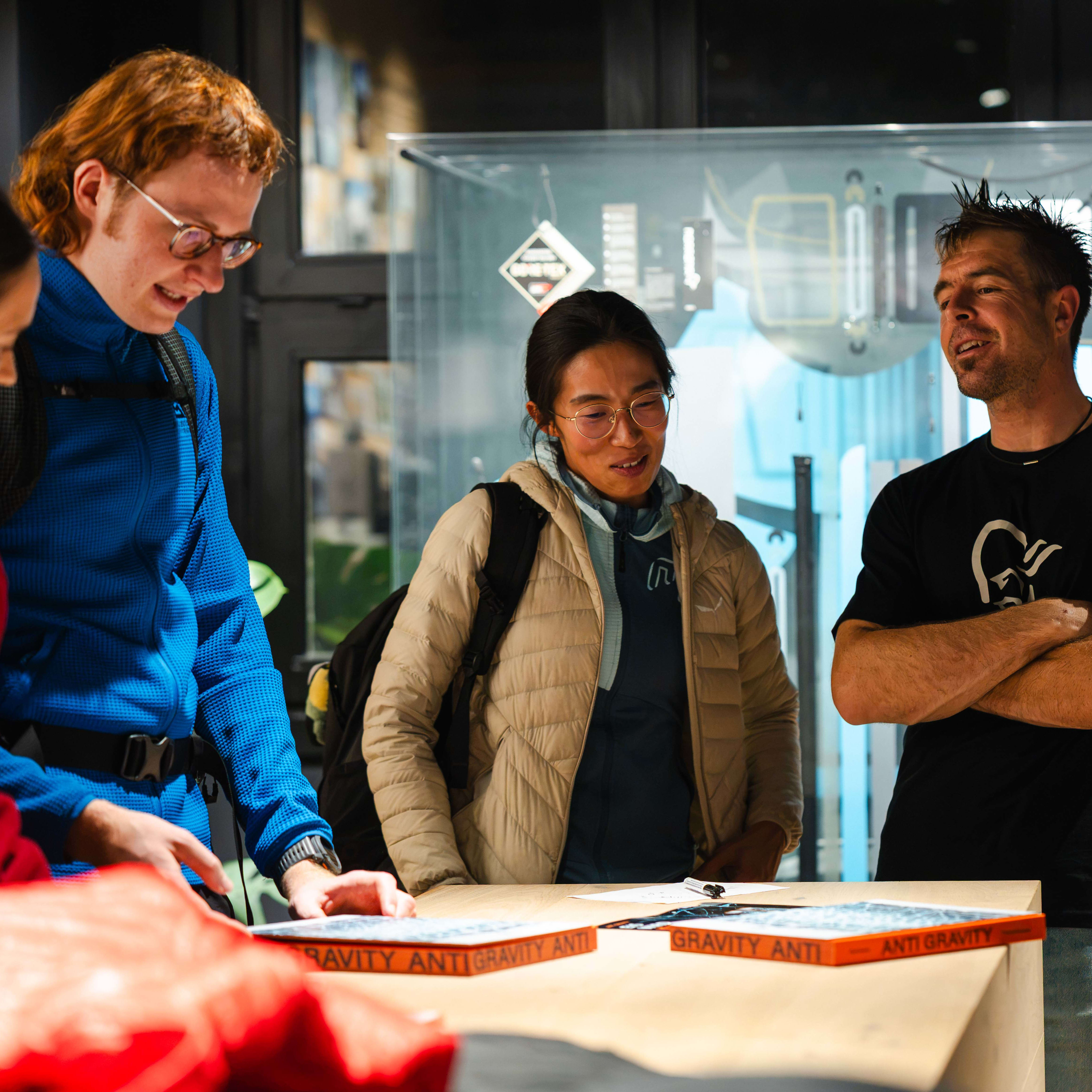 People in Norrøna clothing gathered around a counter looking at 'Anti Gravity' booklets.