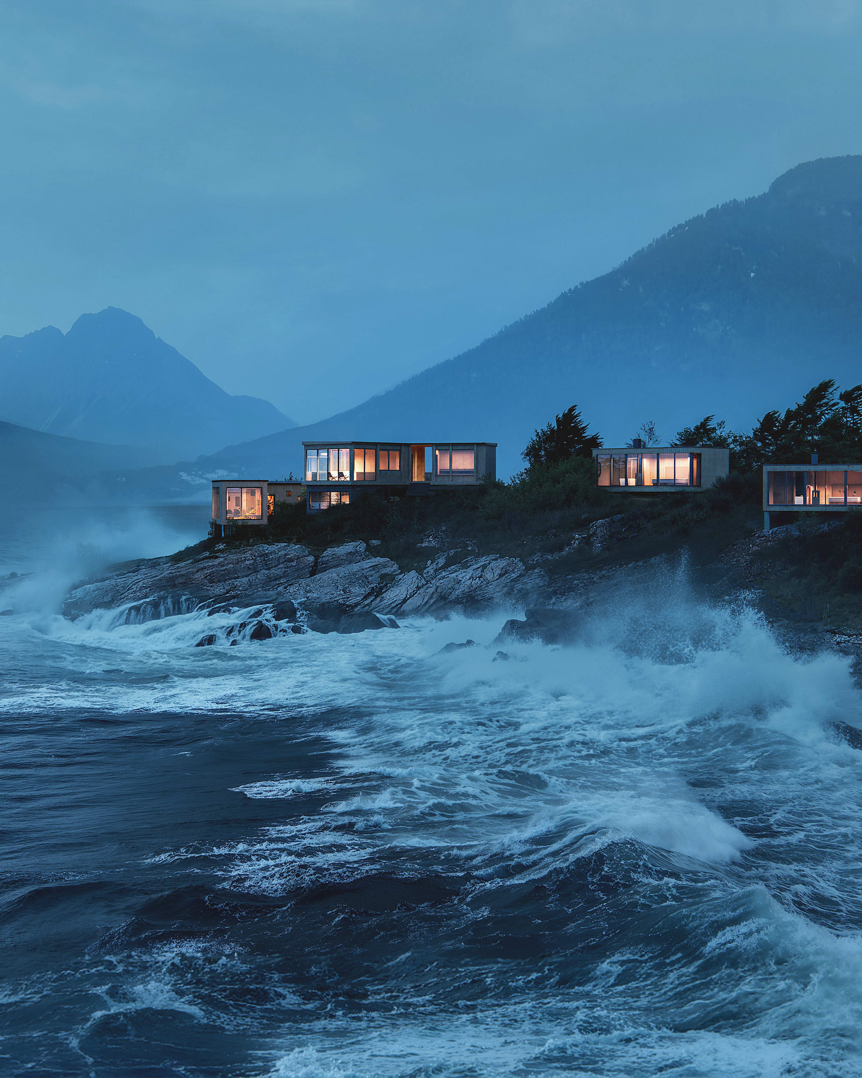 Illuminated modern cabins on a rocky coast with stormy ocean waves crashing, set against misty mountains.