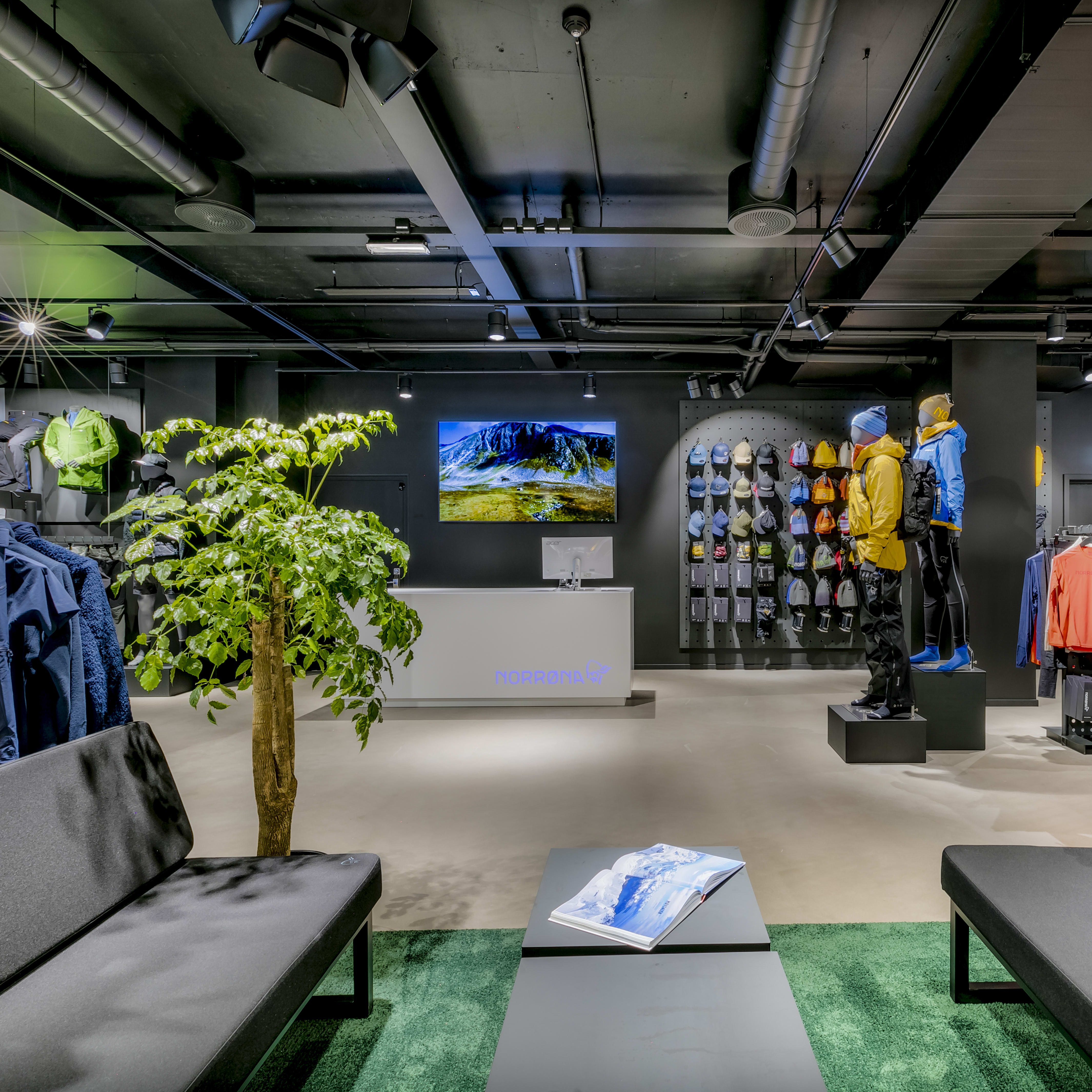 Modern interior of a Norrøna store displaying outdoor clothing on mannequins and clothing racks.