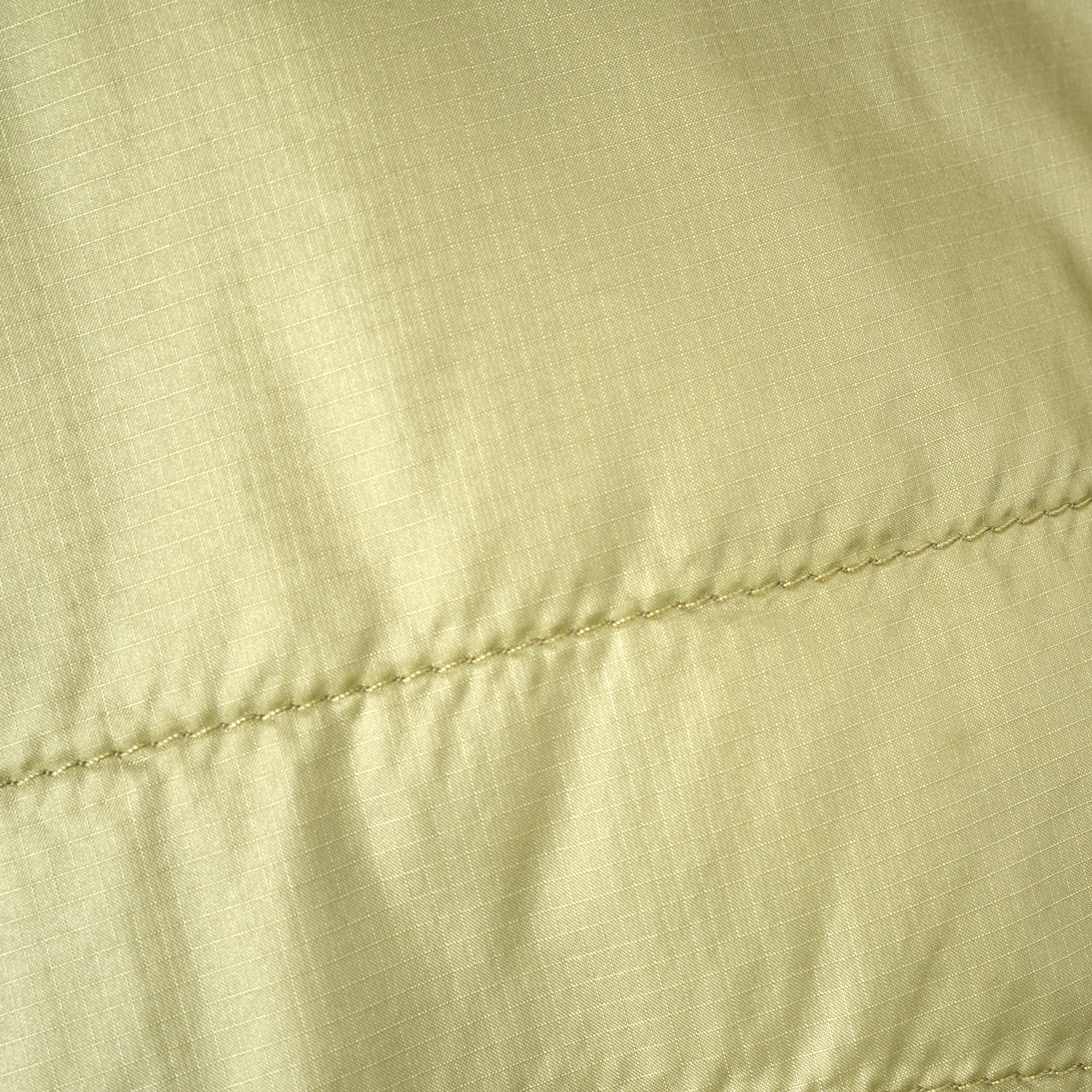 Closeup of a Norrøna jacket's light green fabric with a zipper.