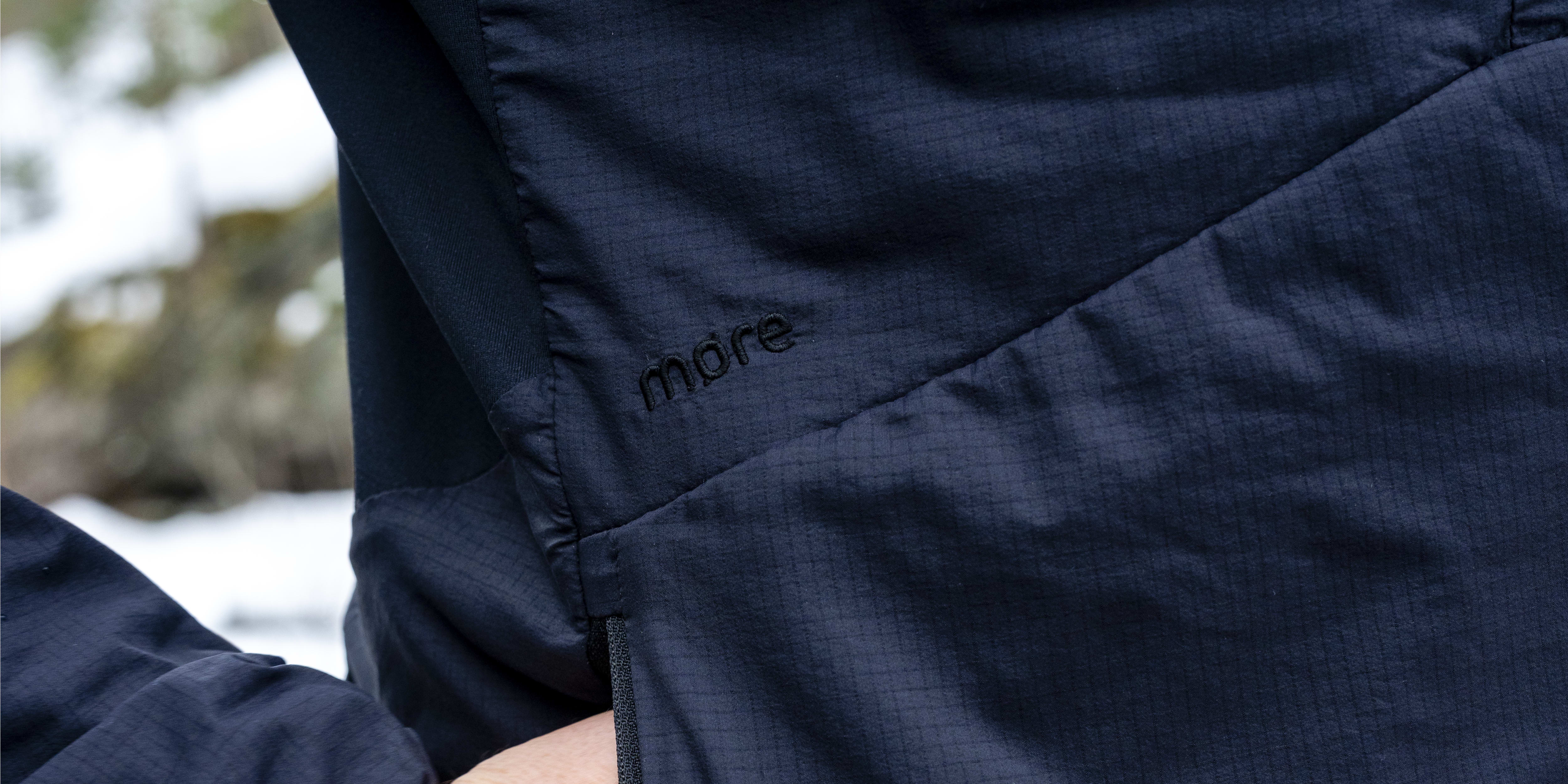 Close-up of a person wearing a navy blue Norrøna jacket with their hand in the pocket. 
