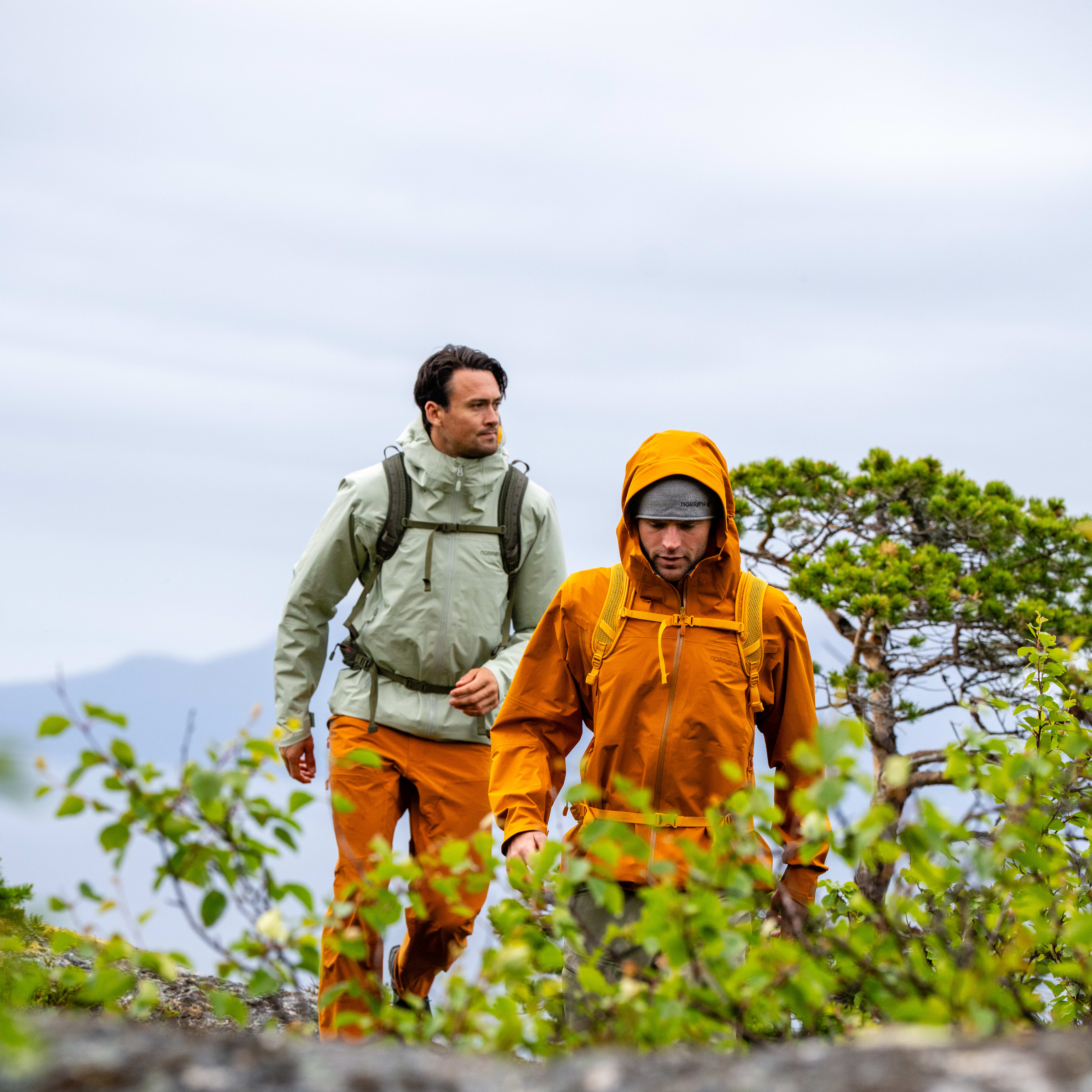 Two men hiking on a rocky trail wearing Norrøna jackets.