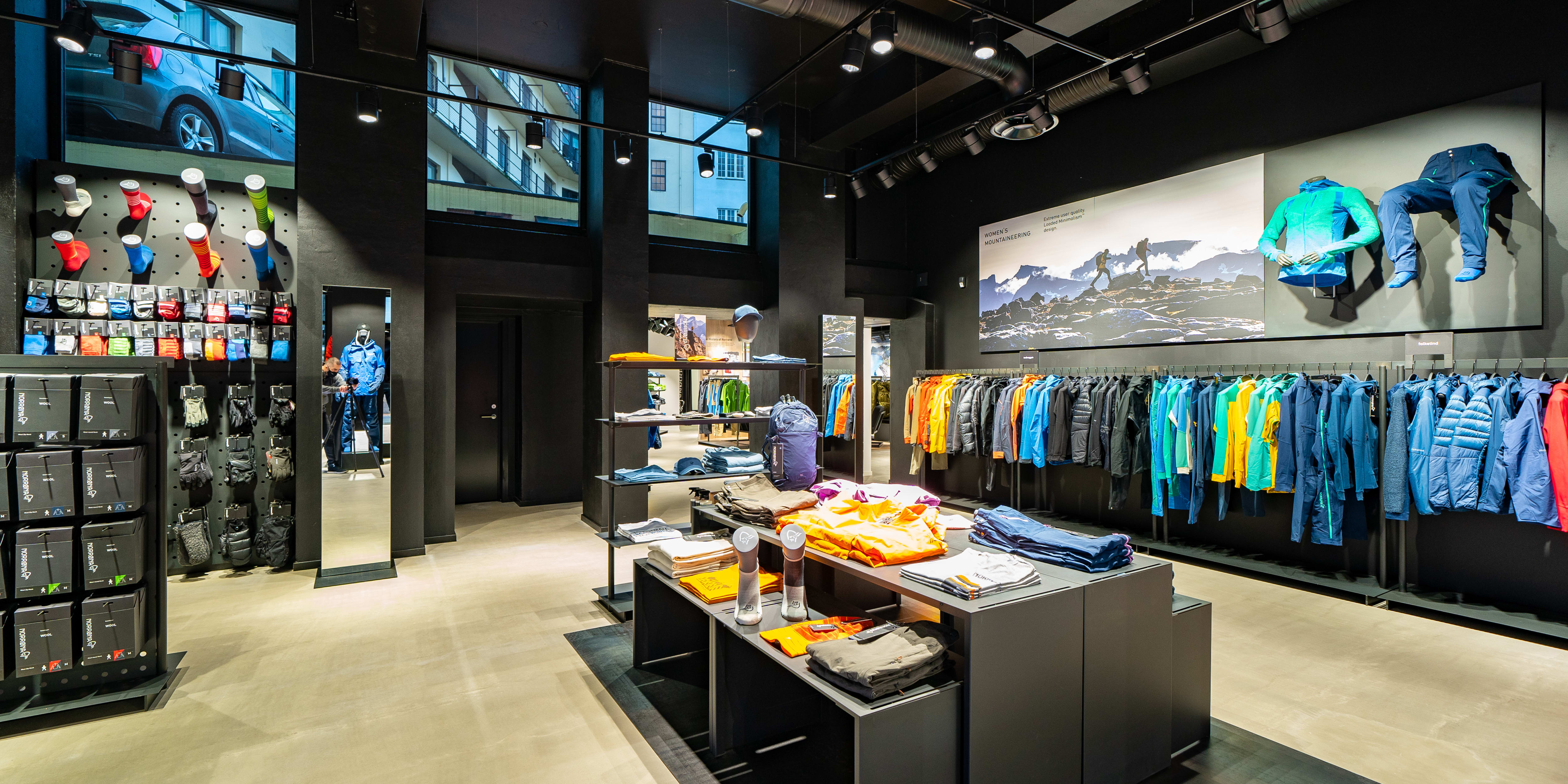 Interior of a modern Norrøna retail store displaying colorful outdoor clothing on racks and shelves.