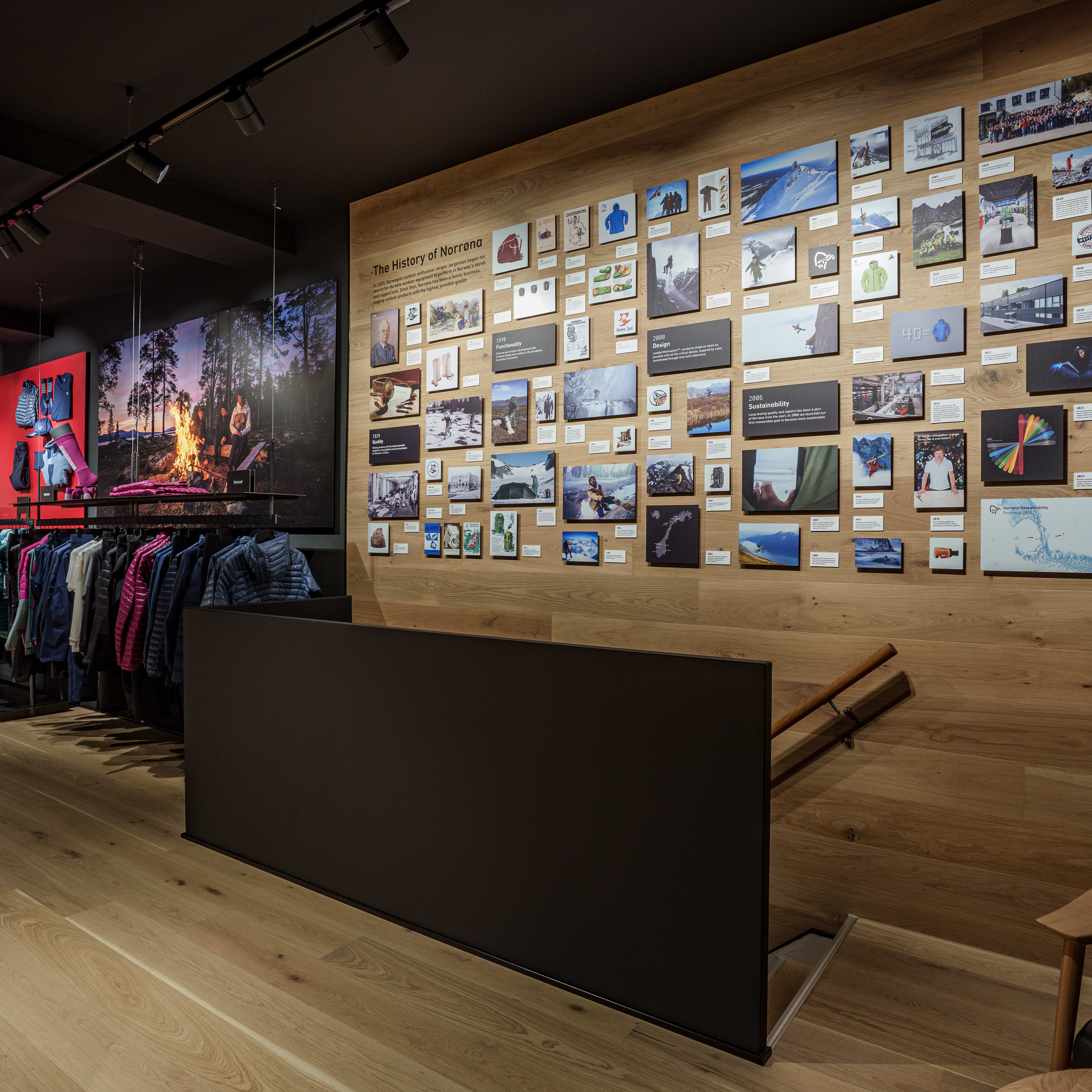 A wall display showcasing the history of Norrøna, a Norwegian outdoor clothing brand. Photos show the brand's evolution and its commitment to sustainability.  
