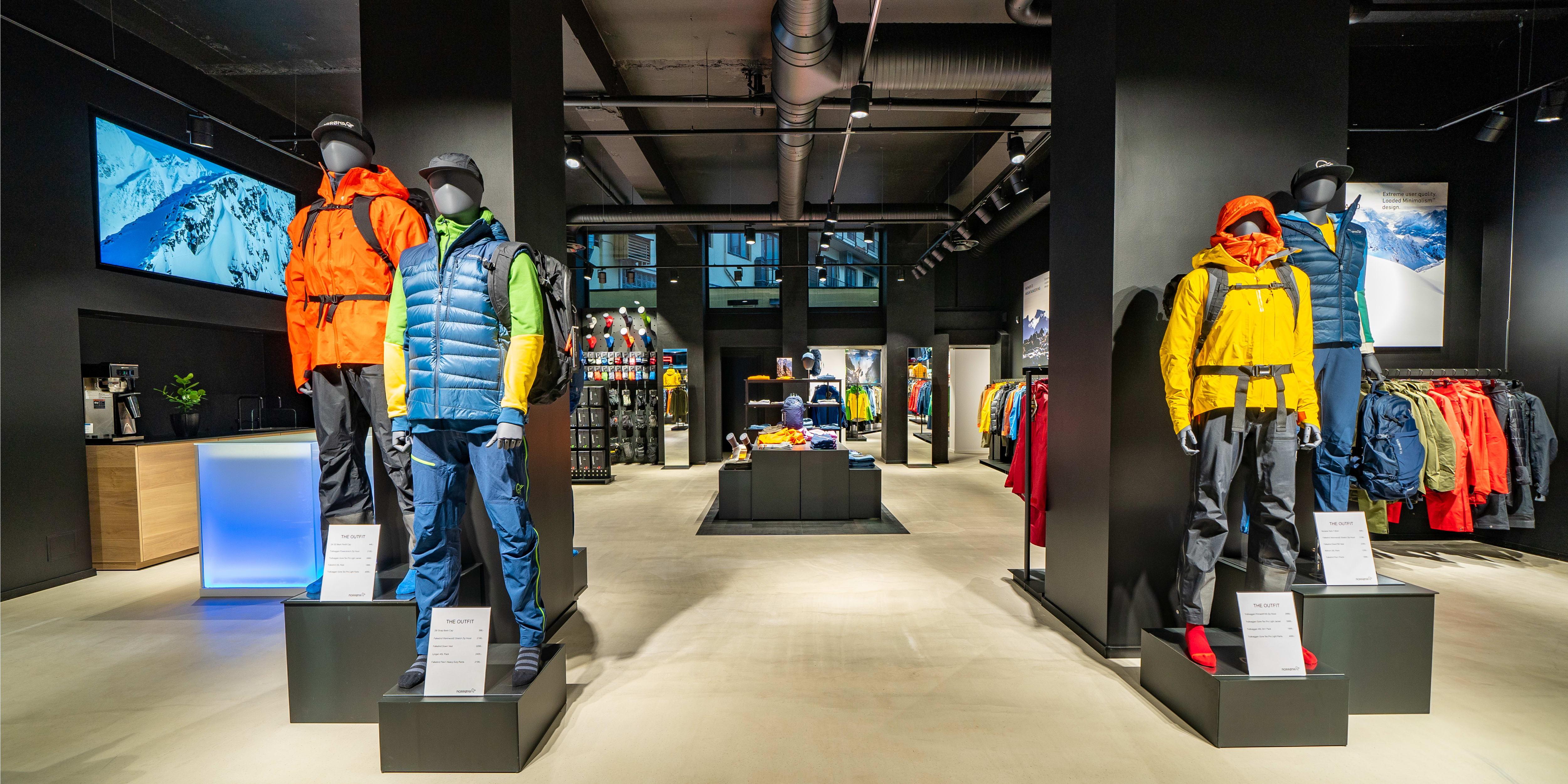 Mannequins displaying colorful Norrøna outdoor clothing inside a modern retail store.