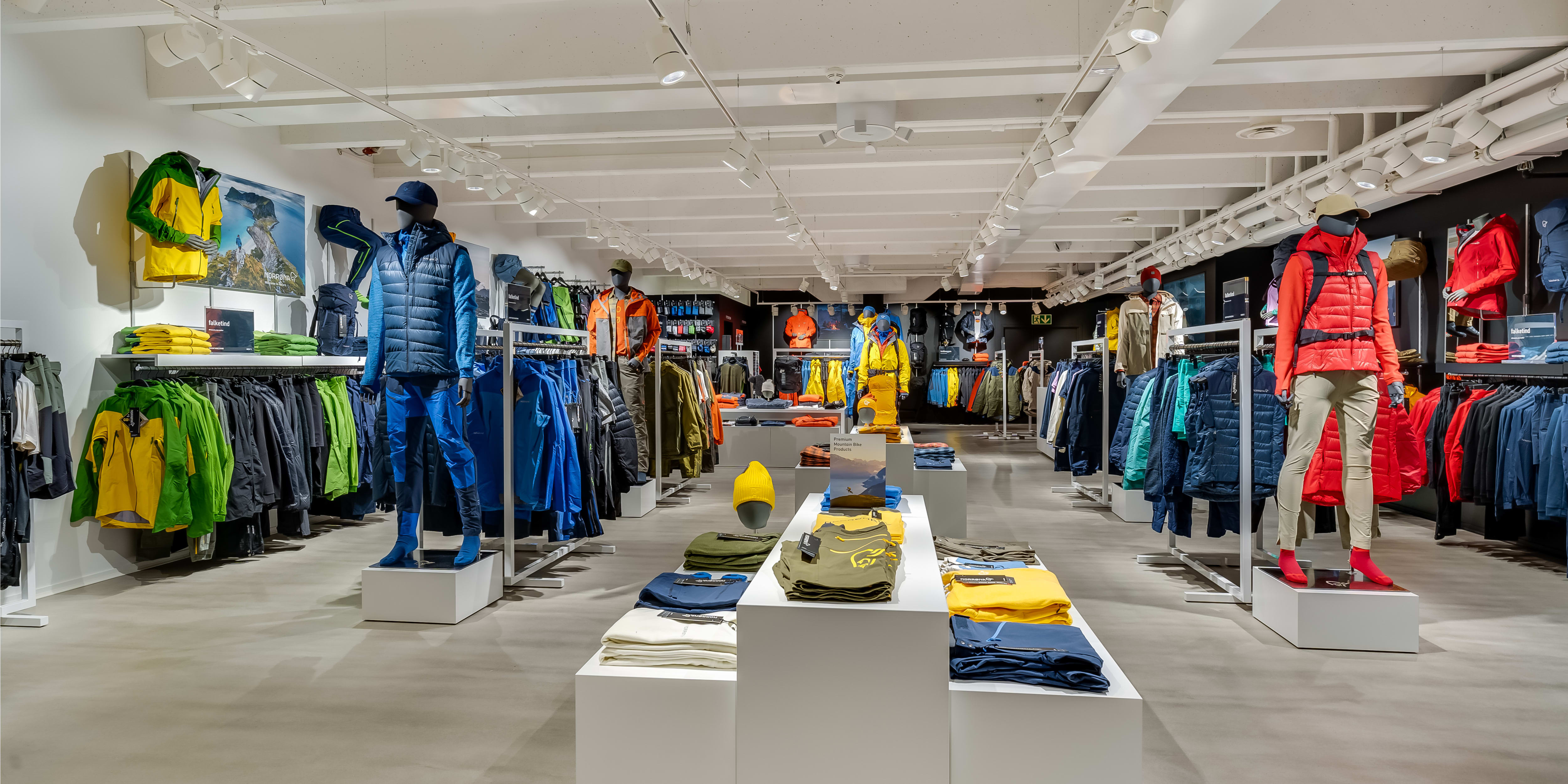 A modern Norrøna retail store displaying colorful outdoor apparel on mannequins and clothing racks.