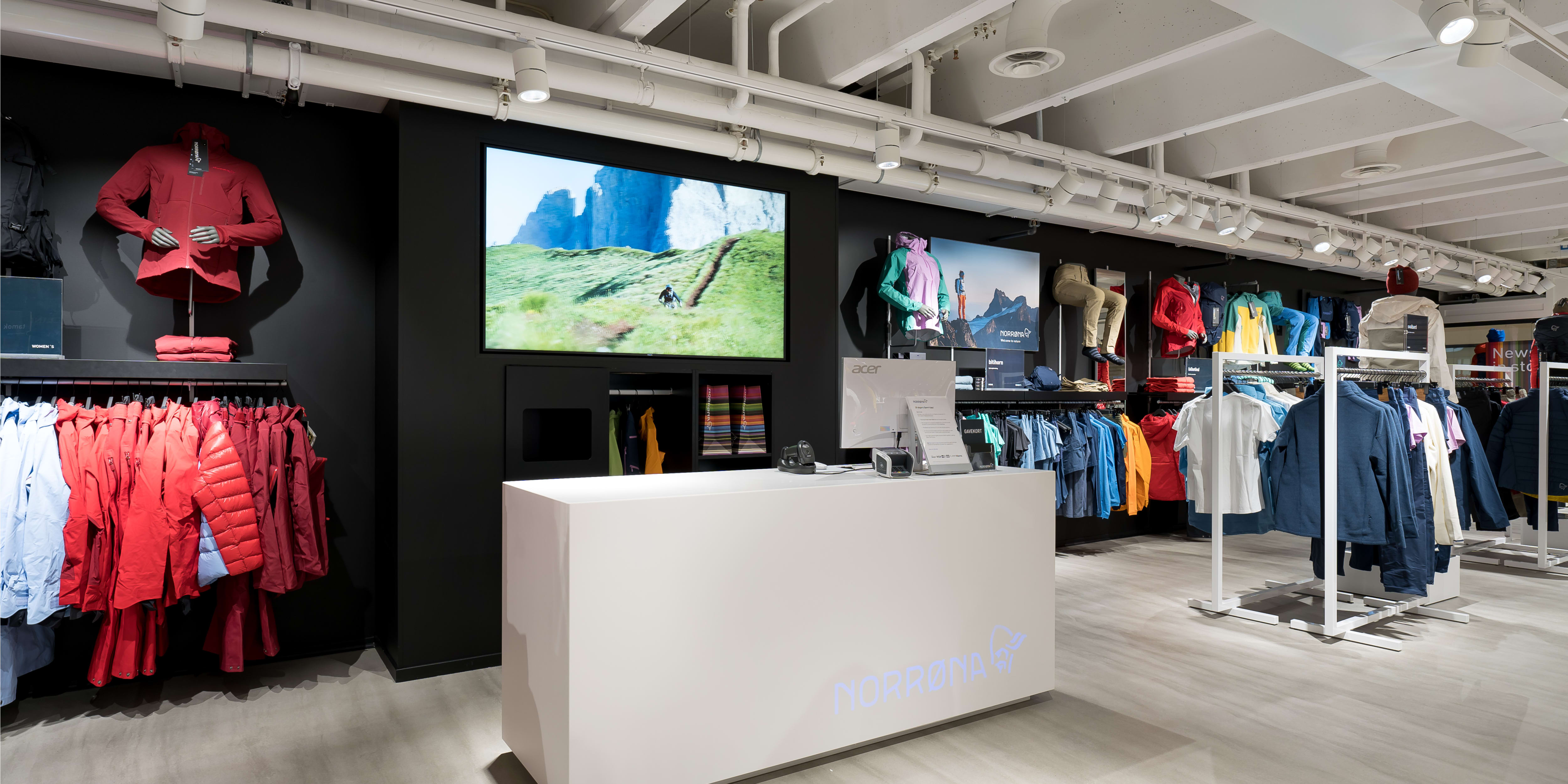 Norrøna retail store interior with colorful outdoor clothing on display racks and a white checkout counter.