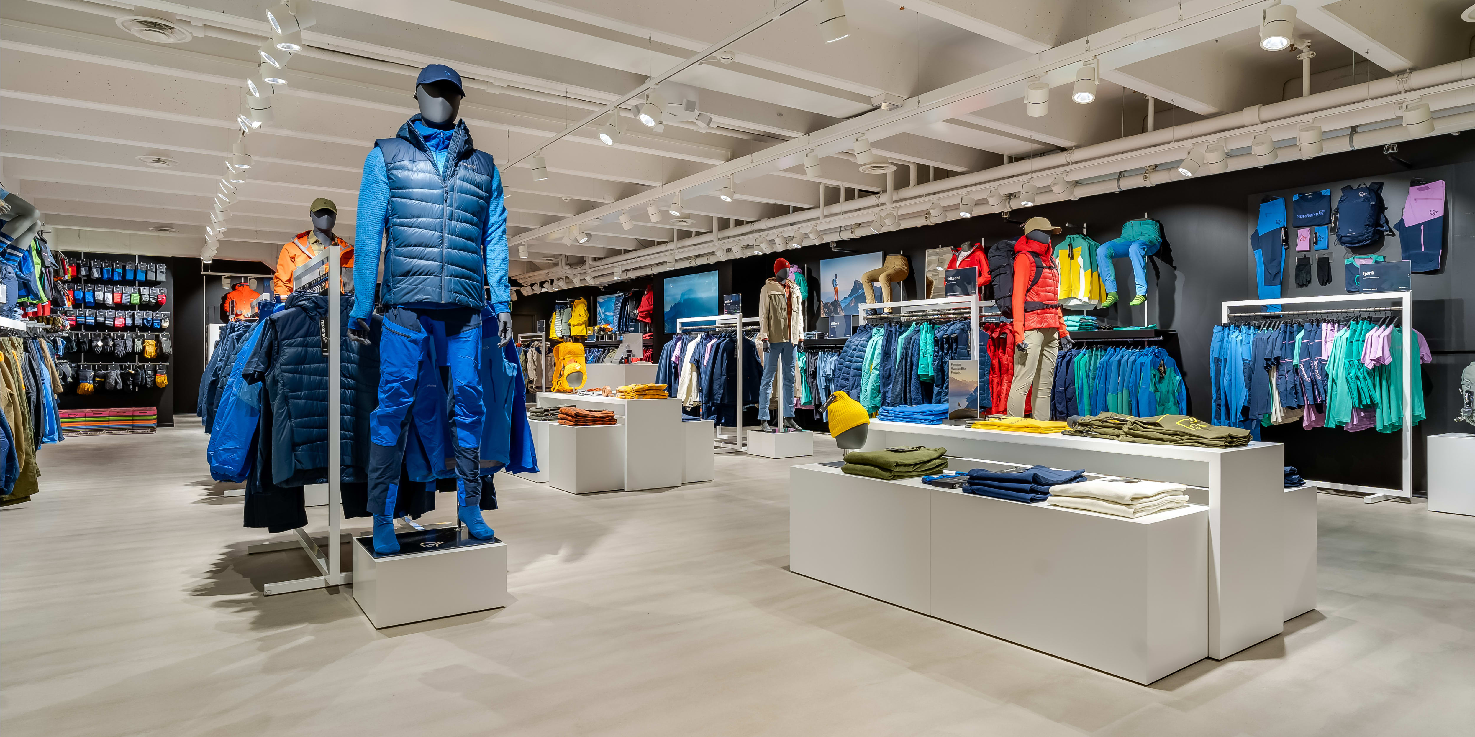 Bright retail store interior displaying colorful Norrøna outdoor clothing on mannequins and display racks.