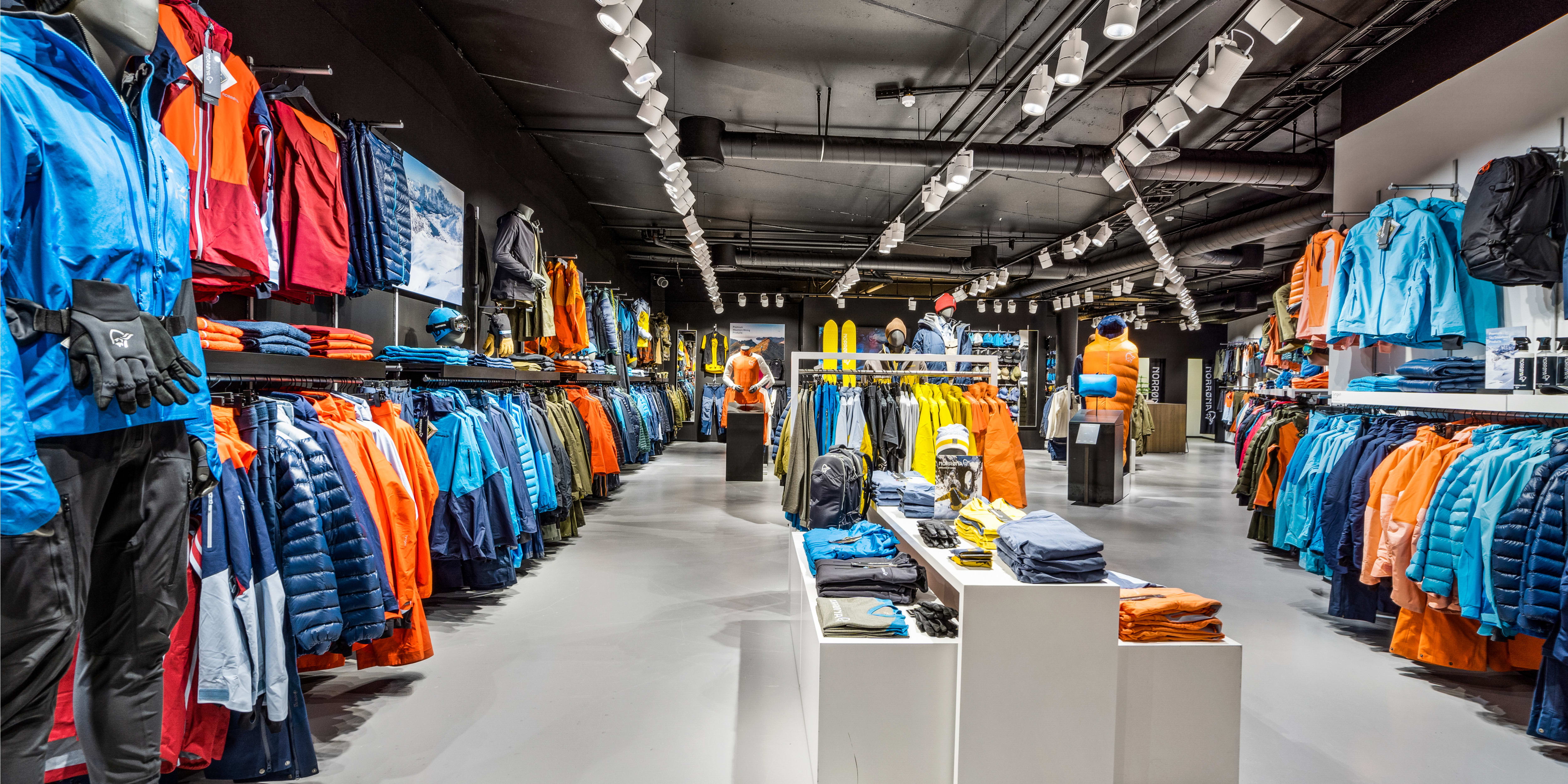 Modern retail store interior filled with colorful Norrøna outdoor clothing on racks and mannequins.