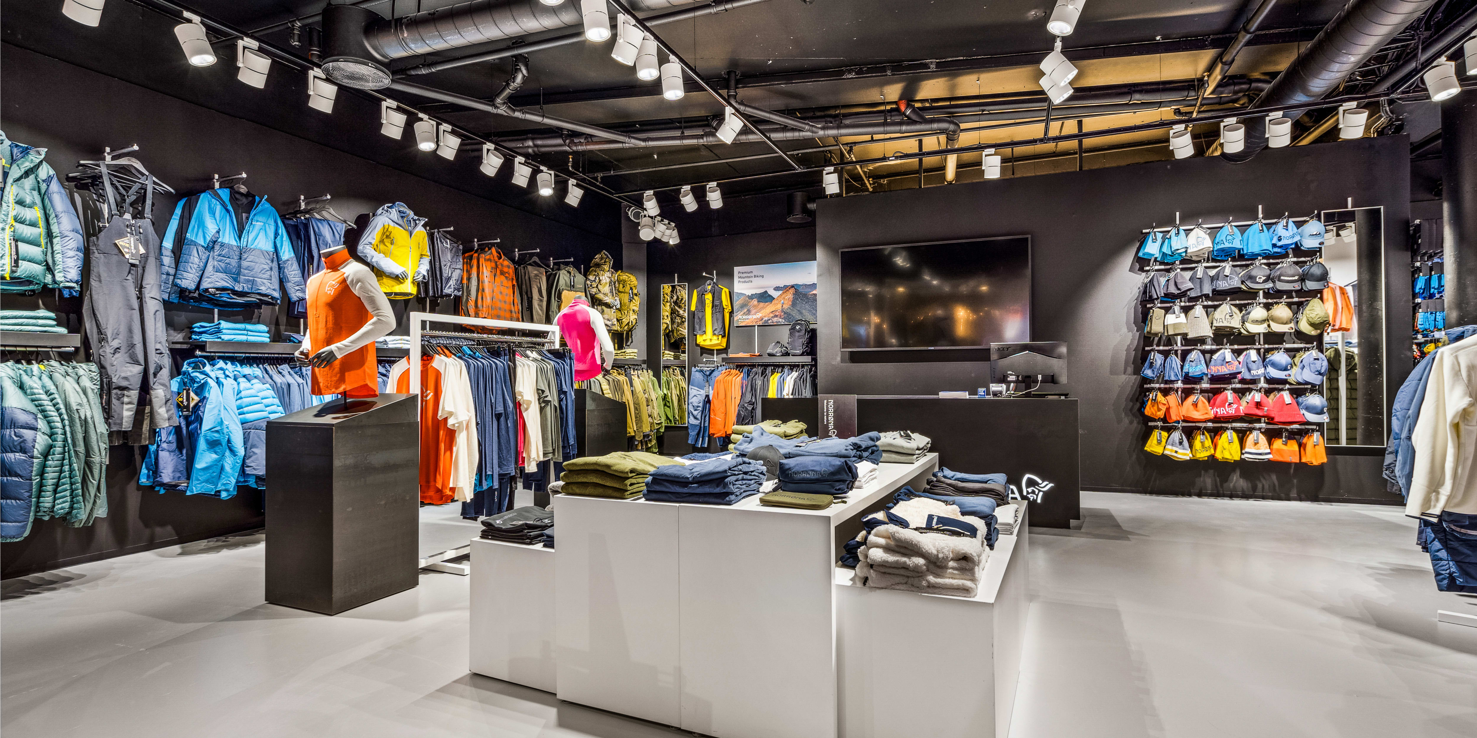 Modern Norrøna retail store interior displaying outdoor clothing on racks, mannequins, and tables.