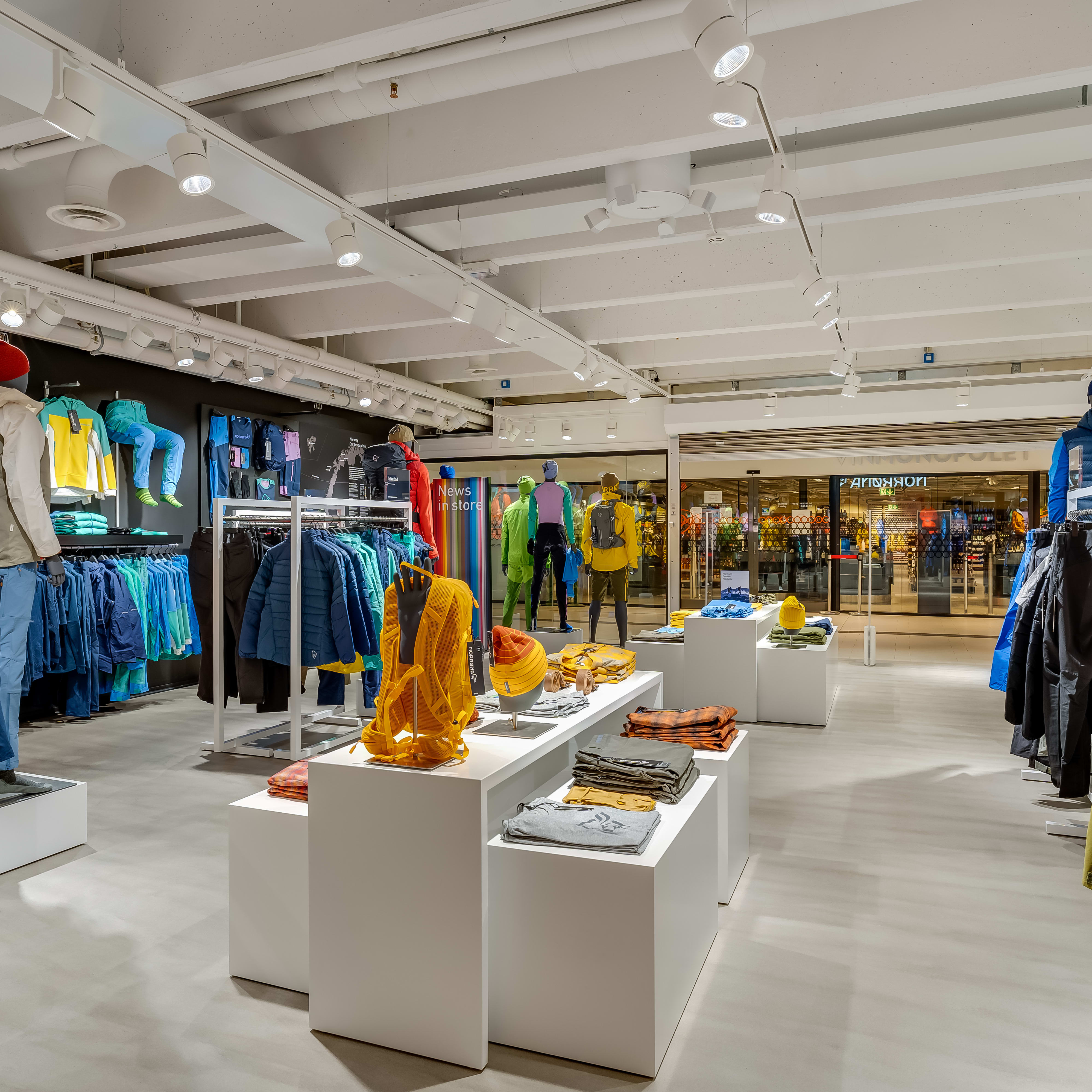 Bright interior of a Norrøna store displaying colorful outdoor clothing, backpacks, and gear.