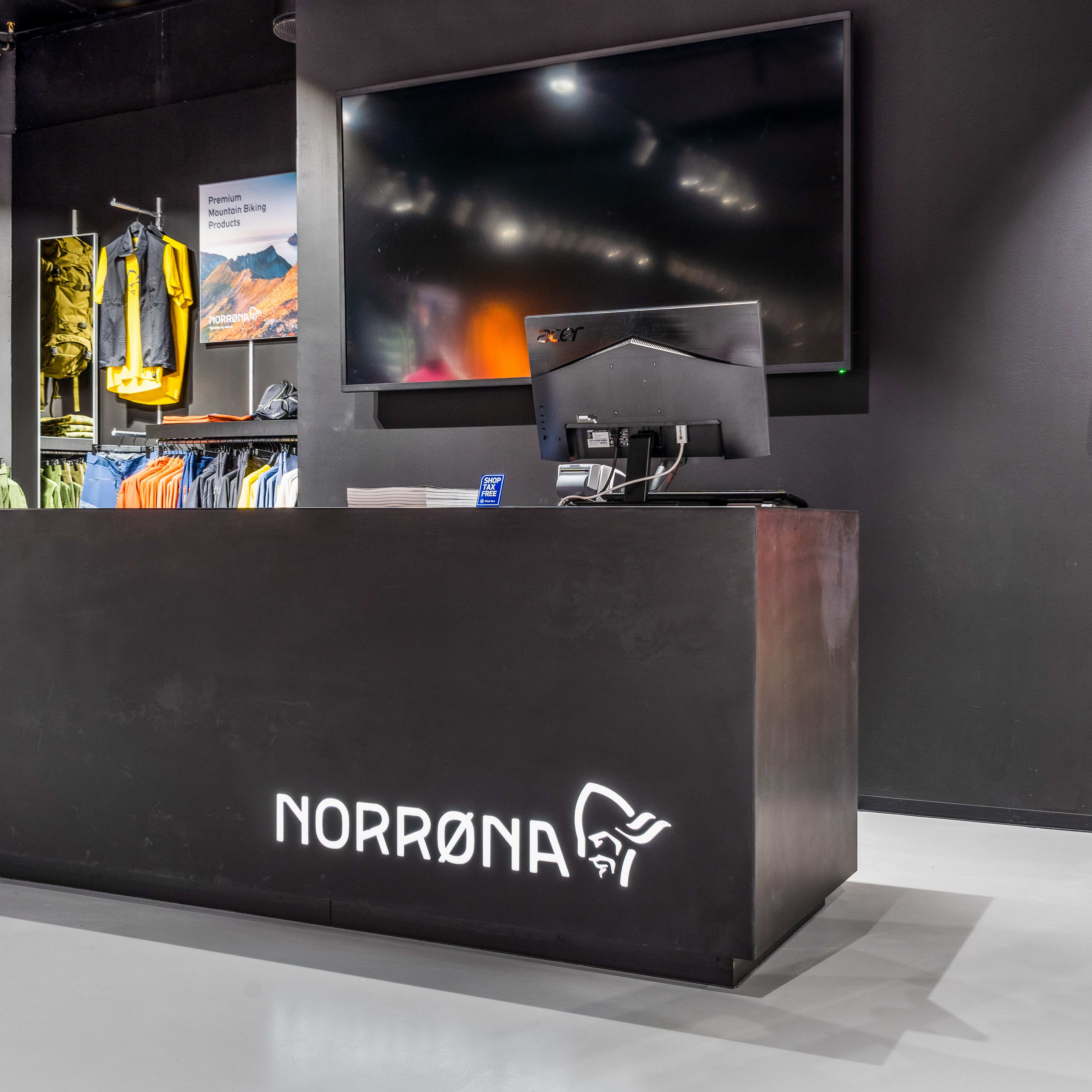 Norrøna store checkout counter with a glowing logo, surrounded by displays of Norrøna outdoor clothing.