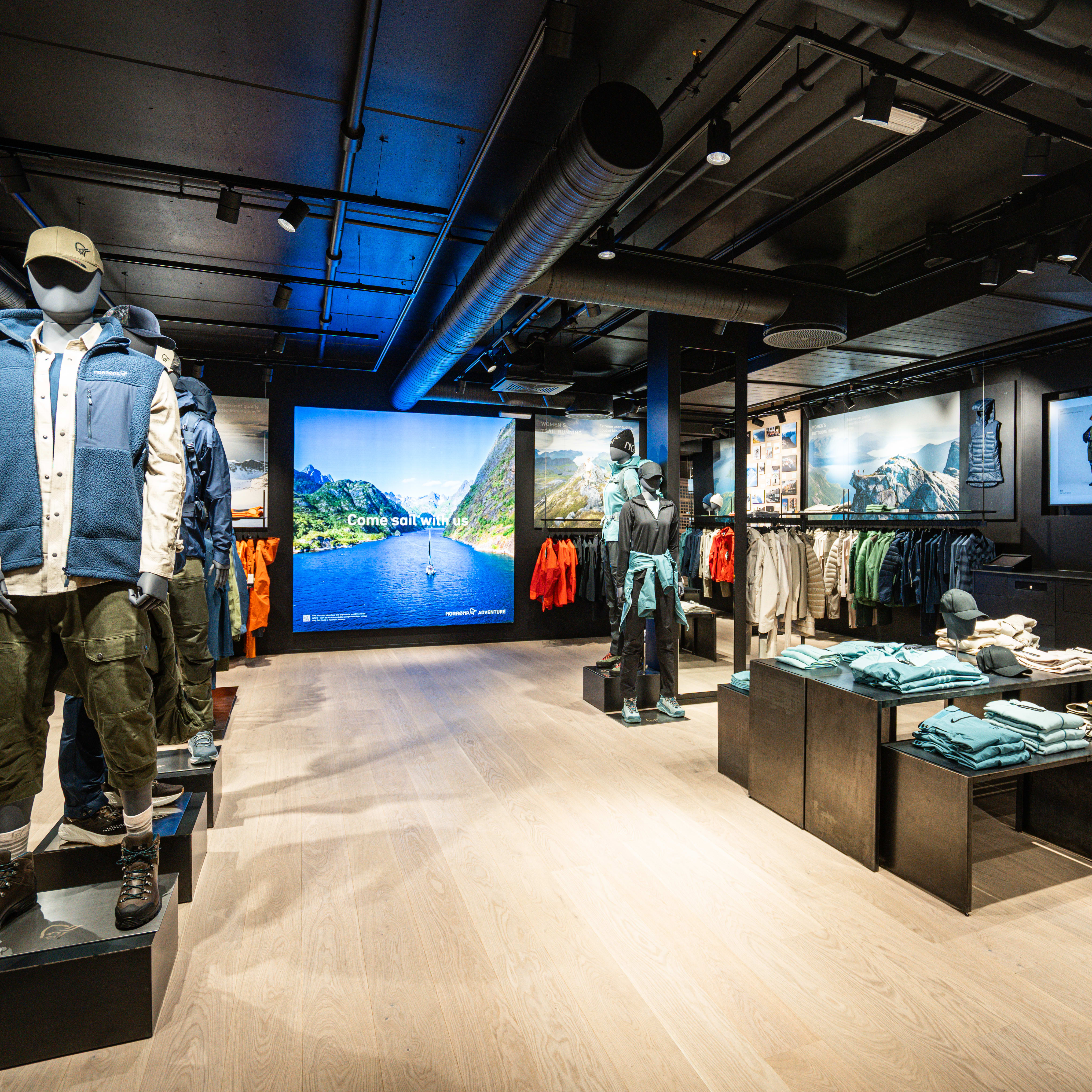 Interior of a Norrøna store featuring mannequins wearing outdoor apparel. Displays feature clothes, packs, and nature imagery.