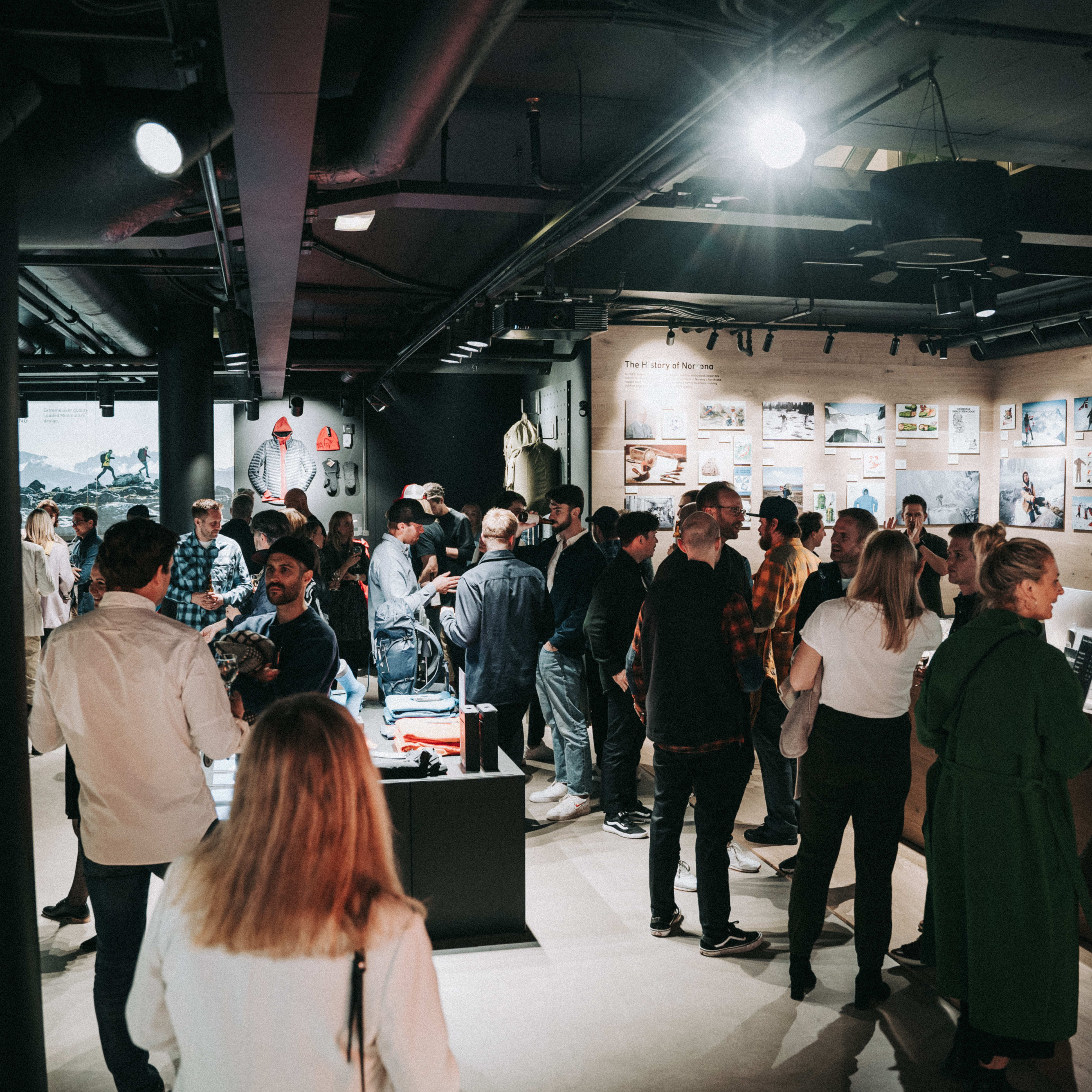 A group of people stand in a Norrøna store, looking at clothing and other merchandise on display.