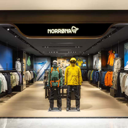 A Norrøna store entrance featuring mannequins in green and yellow jackets, and racks of colorful Norrøna clothing on display.