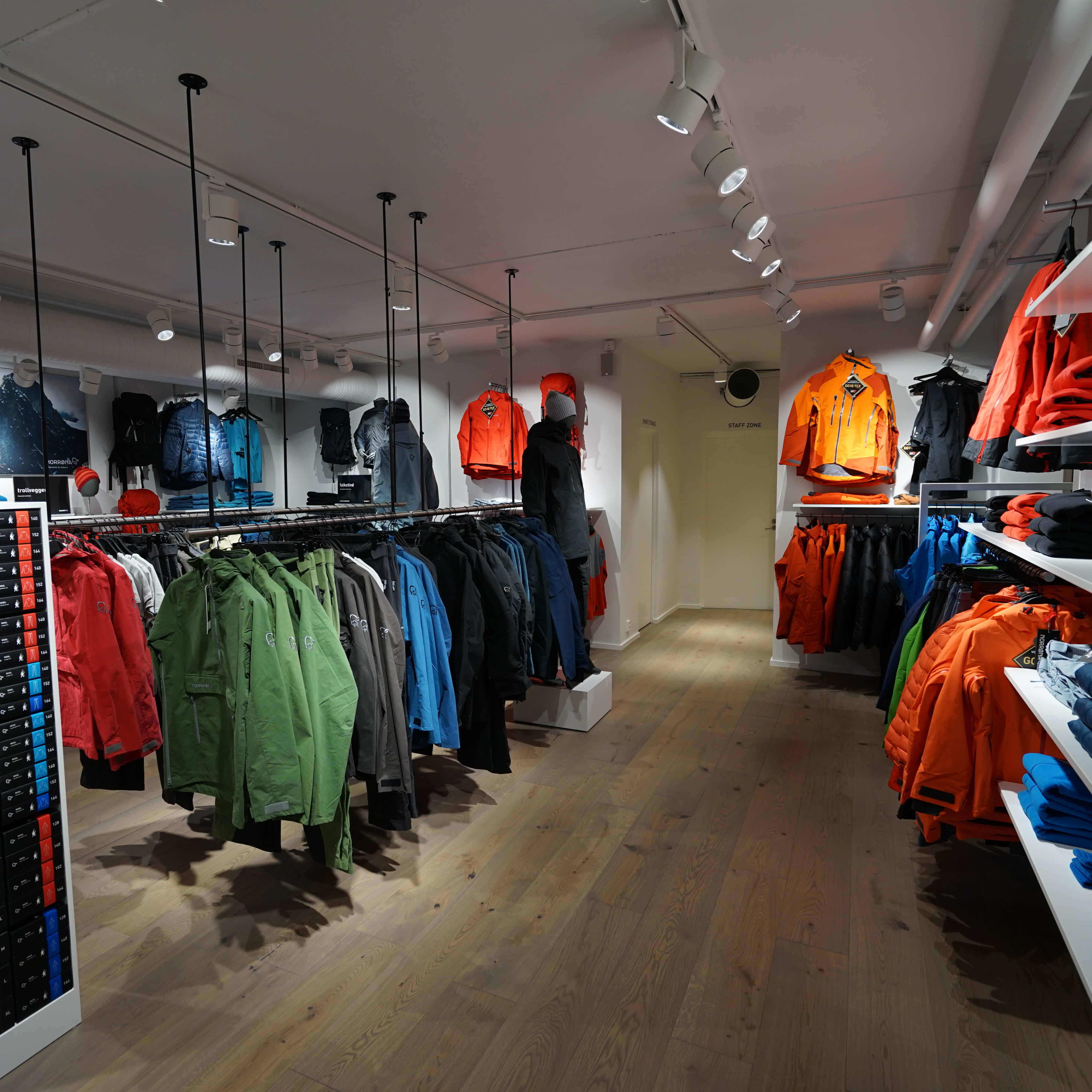 Interior of a Norrøna store displaying colorful outdoor apparel on hanging racks and shelves.