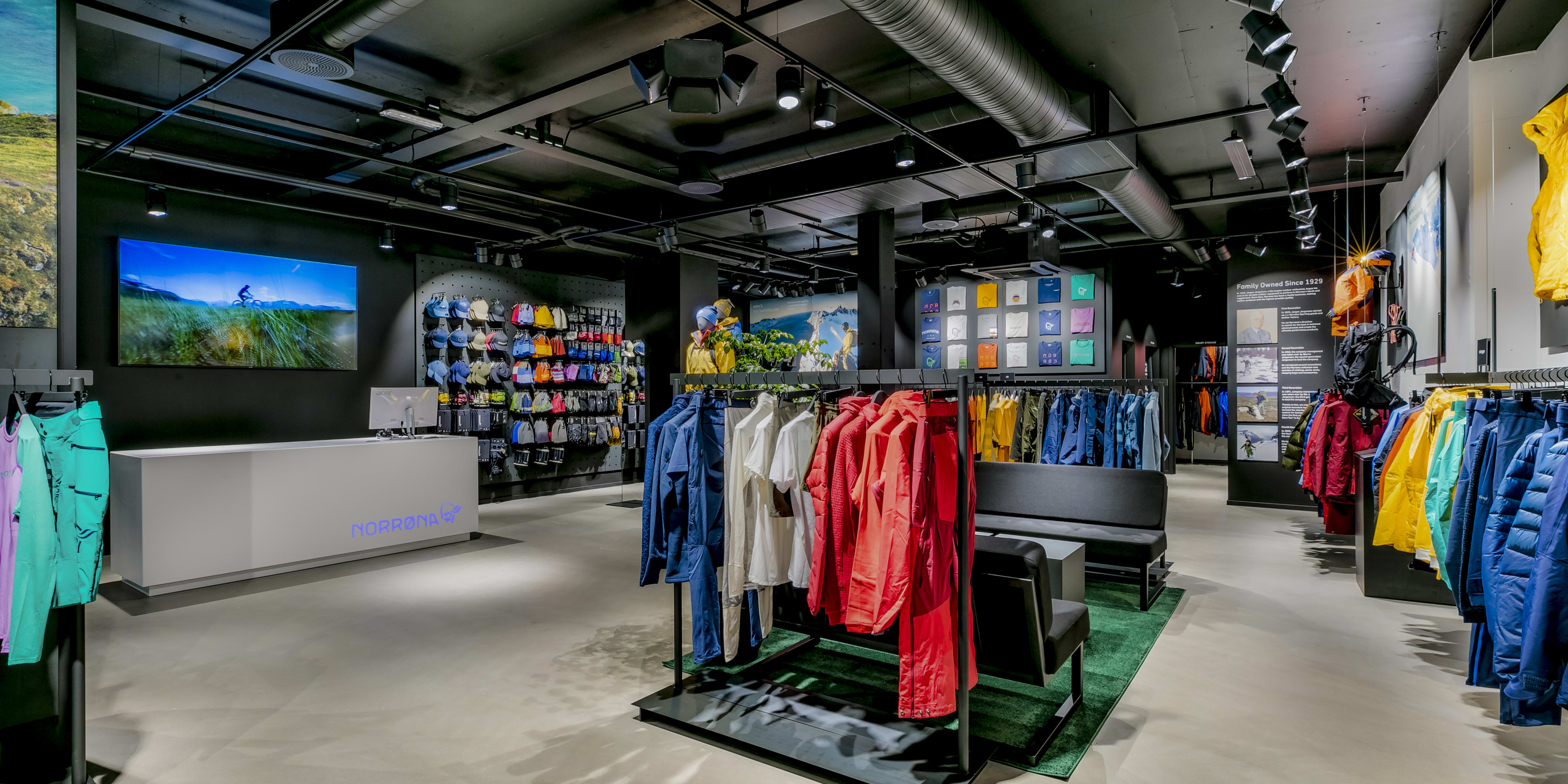 Norrøna retail store interior featuring racks of colorful outdoor clothing and a modern service counter.