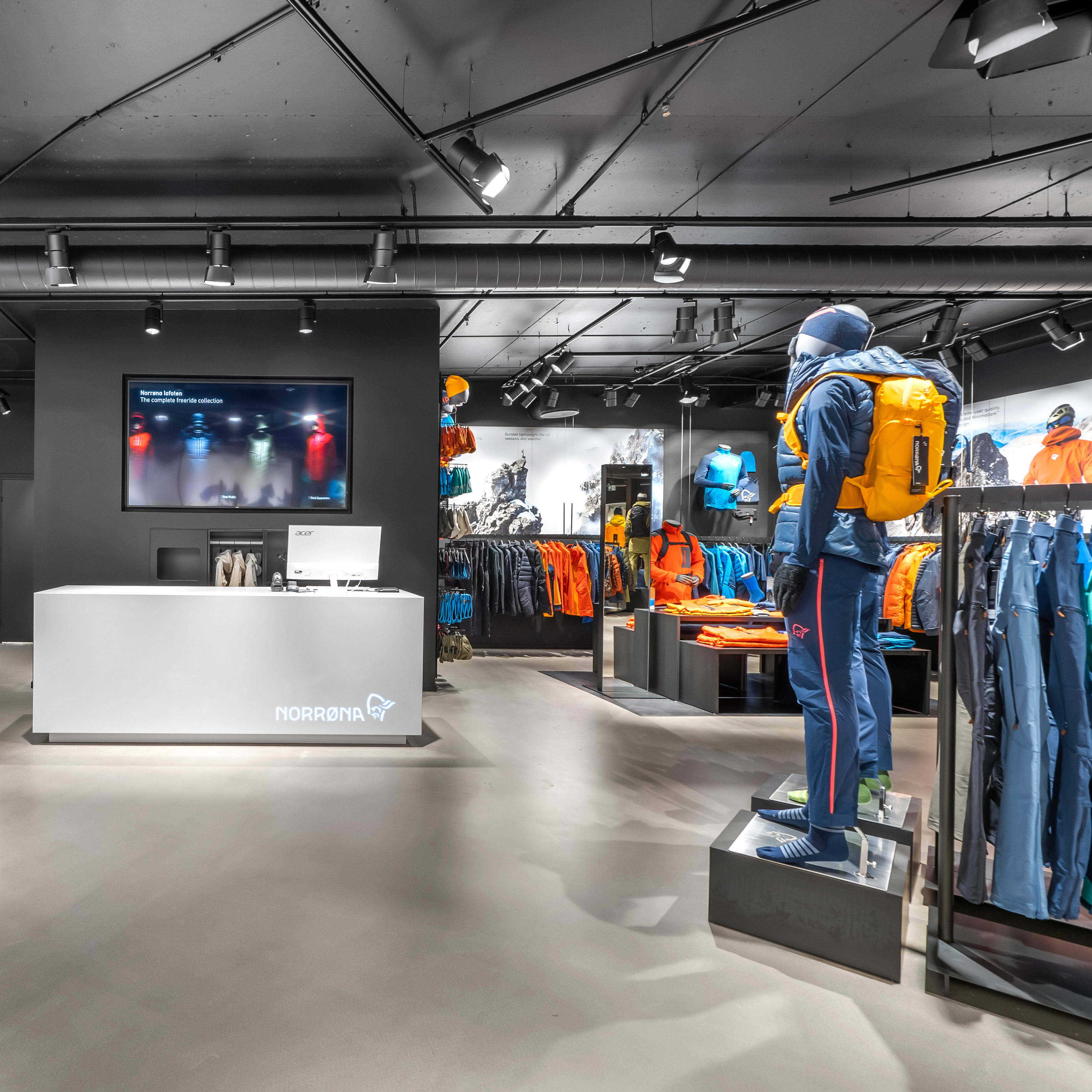 Interior of a Norrøna retail store featuring colorful outdoor clothing displays and a central white counter.
