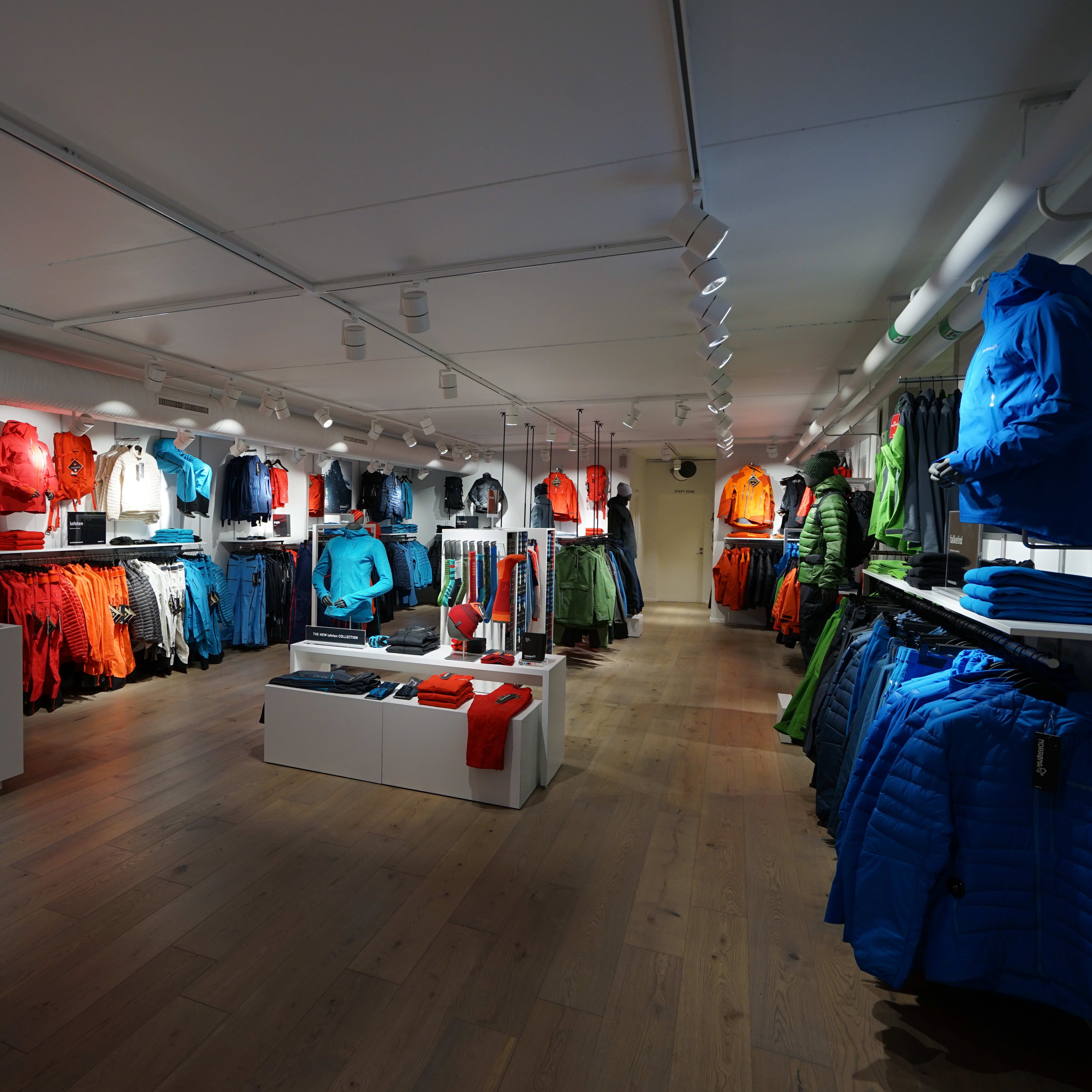 Interior of a Norrøna retail store filled with colorful outdoor clothing, jackets, and displays.