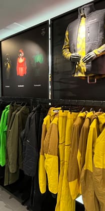 A Norrøna store interior with clothing racks displaying a variety of jackets and vests.  A mannequin is wearing a Norrøna vest.