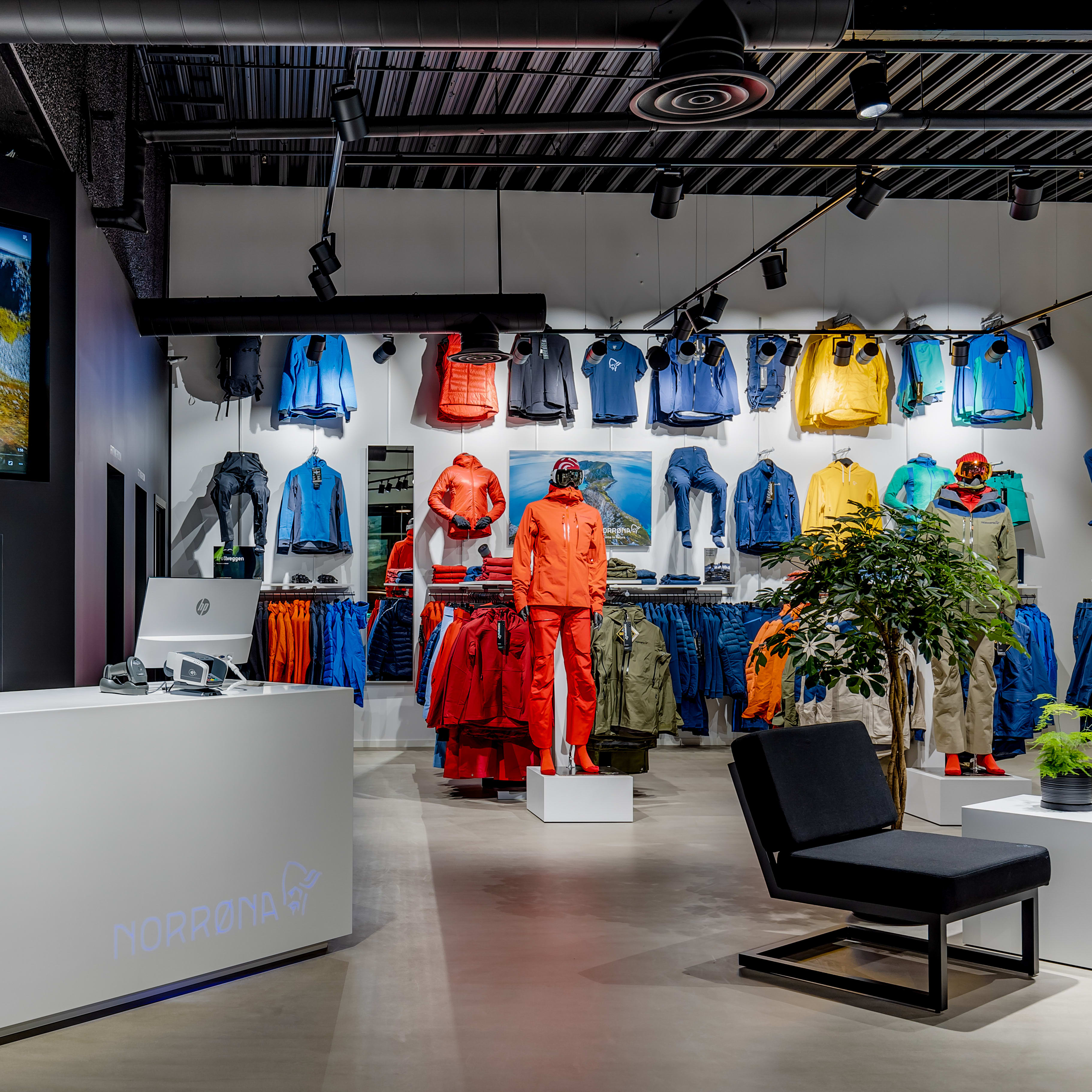 Modern Norrøna store interior with a white checkout counter and colorful Norrøna products on display.