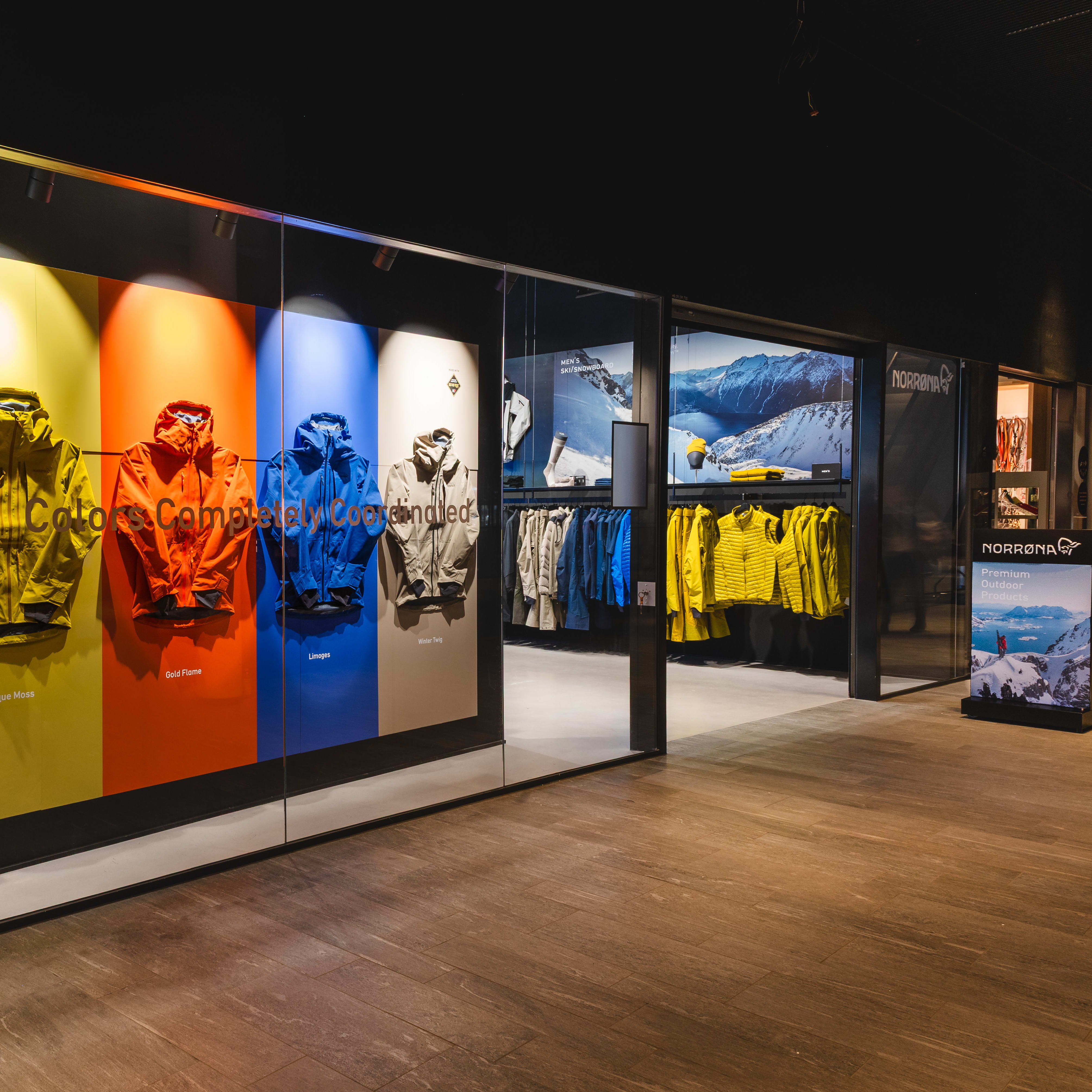 Store display of Norrøna Lofoten jackets in white, yellow, orange, blue, and brown. "Colors Completely Coordinated" text overlays the jackets.