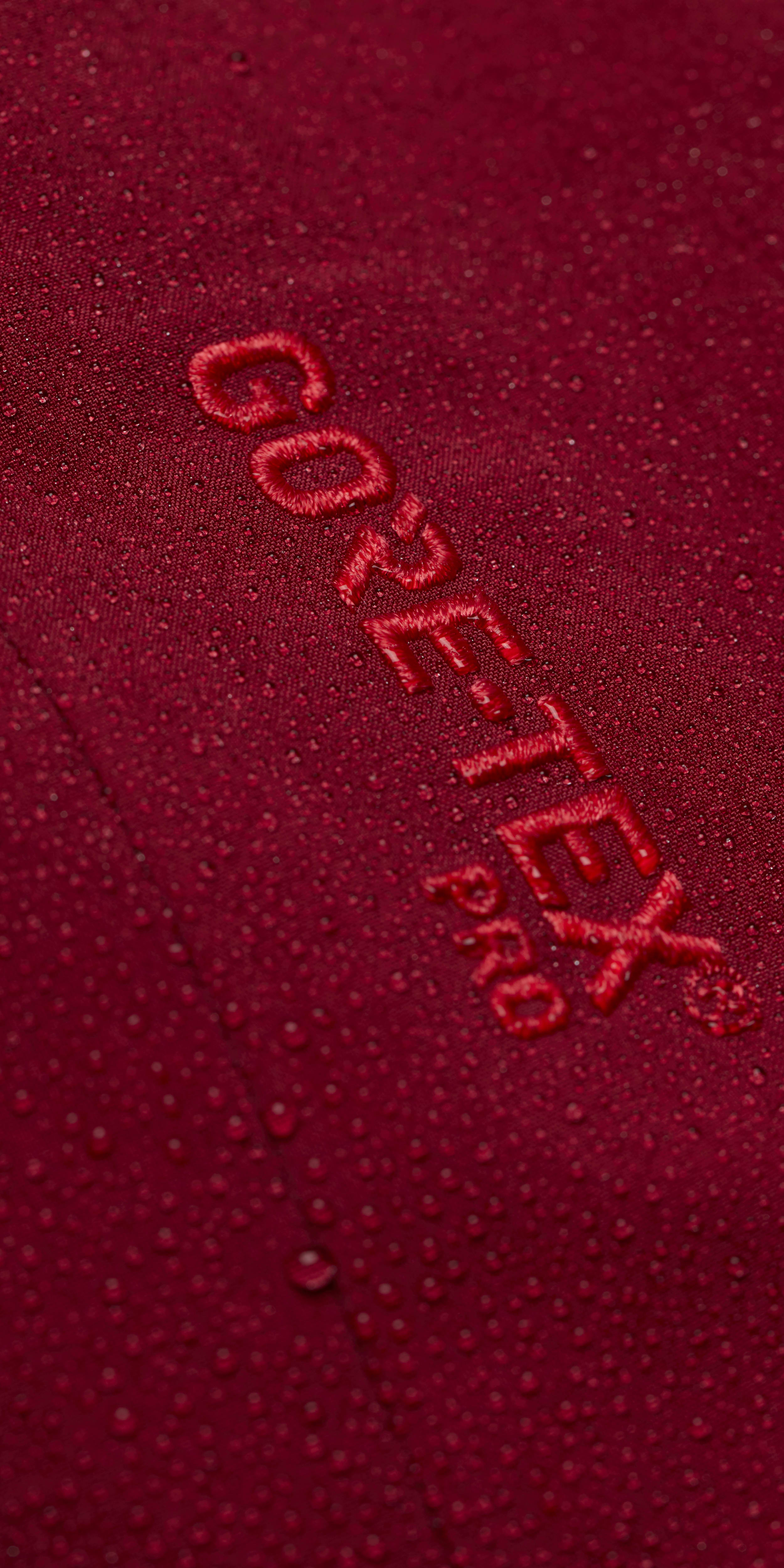 Close-up of a red Norrøna jacket with water droplets.  The "GORE-TEX Pro" logo is visible. 
