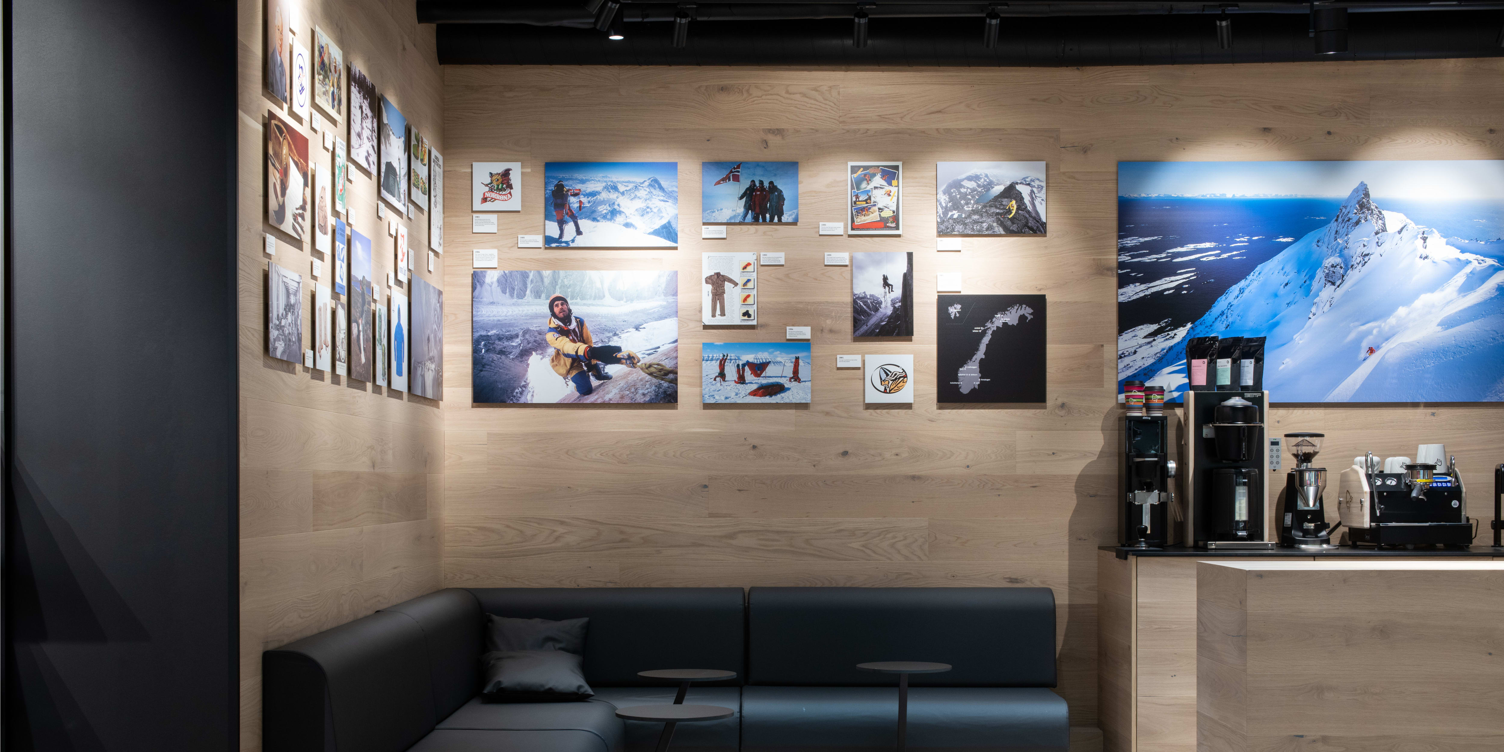 A Norrøna store interior with wooden walls, a black leather sofa, and a coffee bar. 
