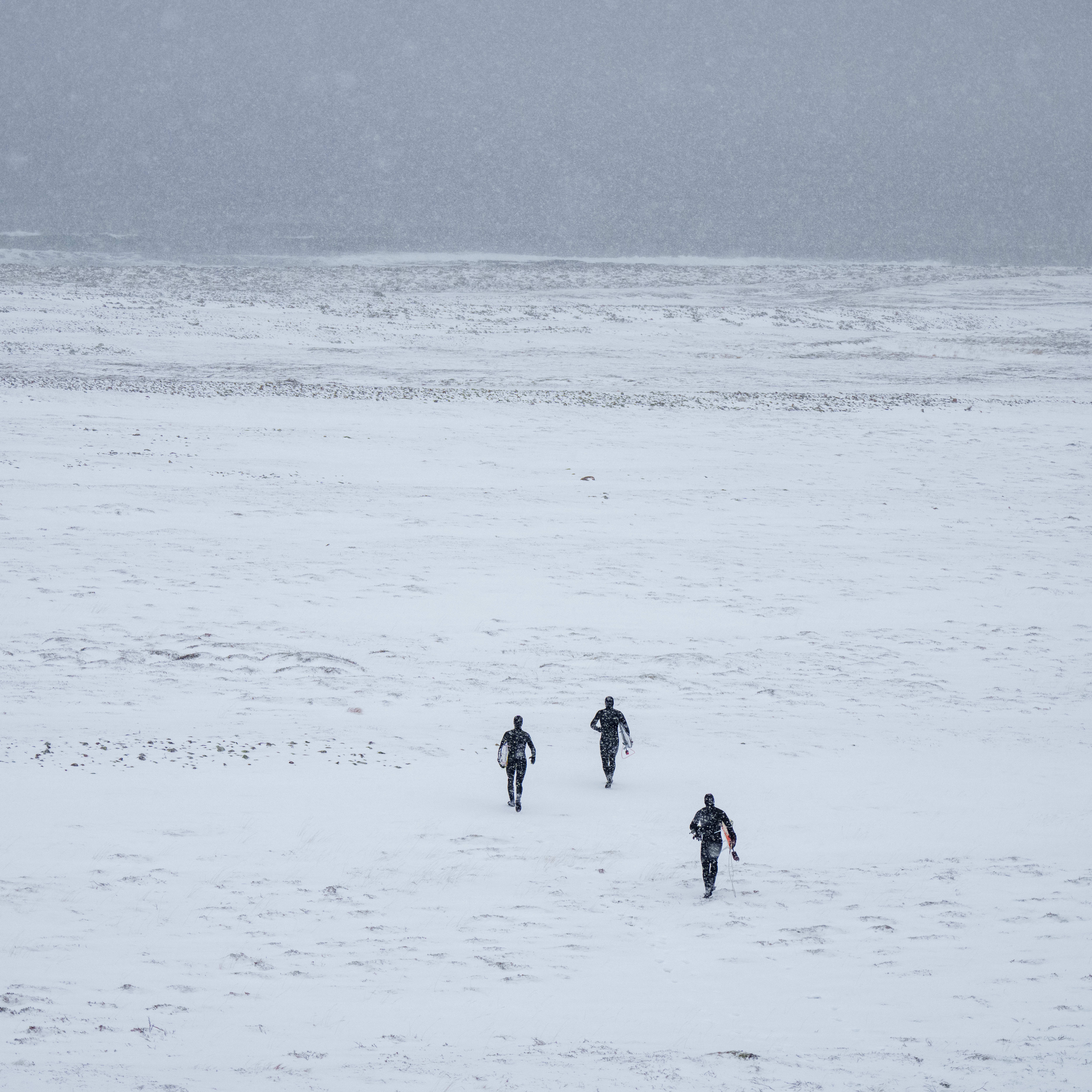 Three people in Norrøna gear walking across a snowy field.