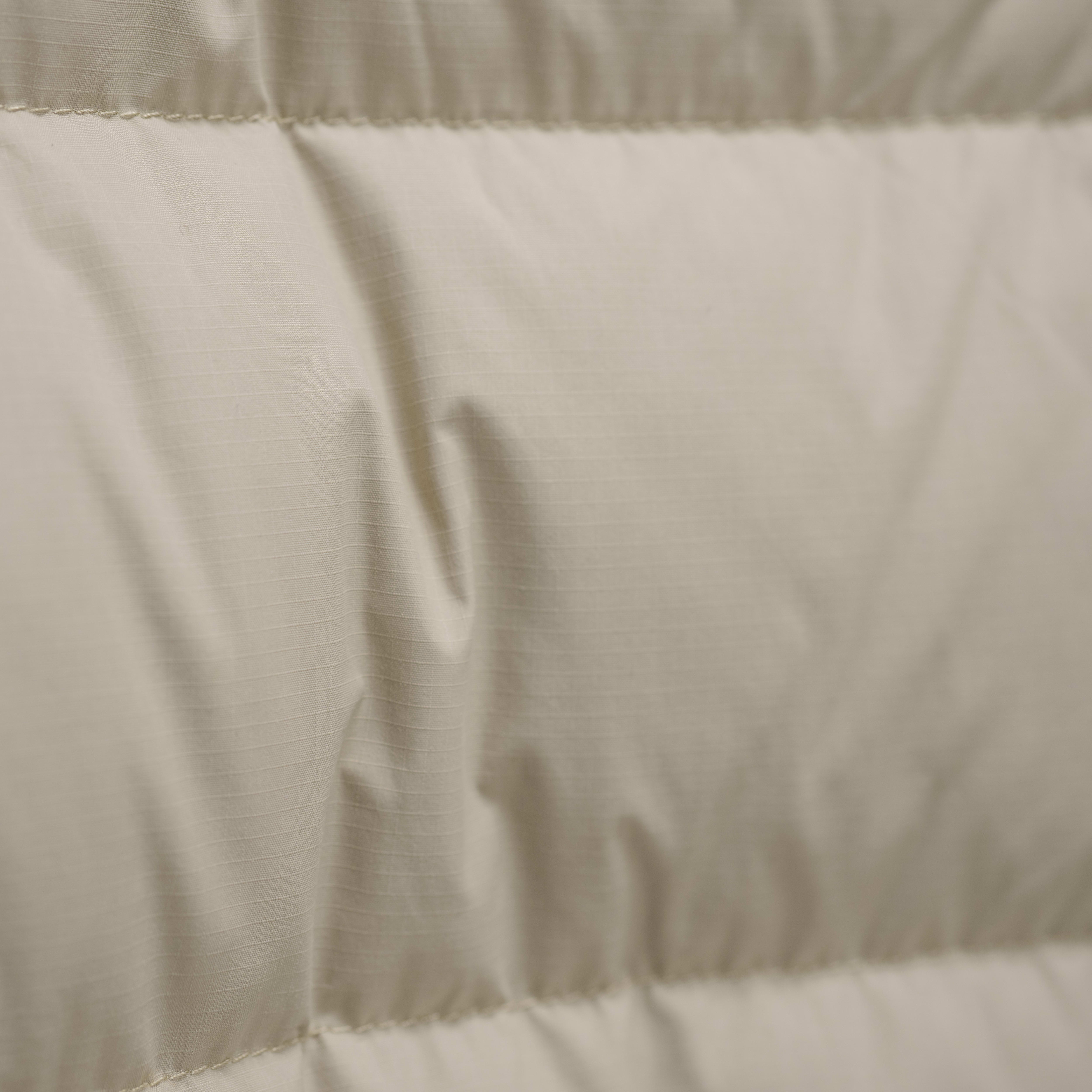Close-up of a beige Norrøna jacket's quilted fabric. 
