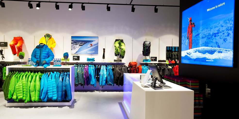 Interior of a Norrøna retail store featuring colorful outdoor clothing displays and a checkout counter.