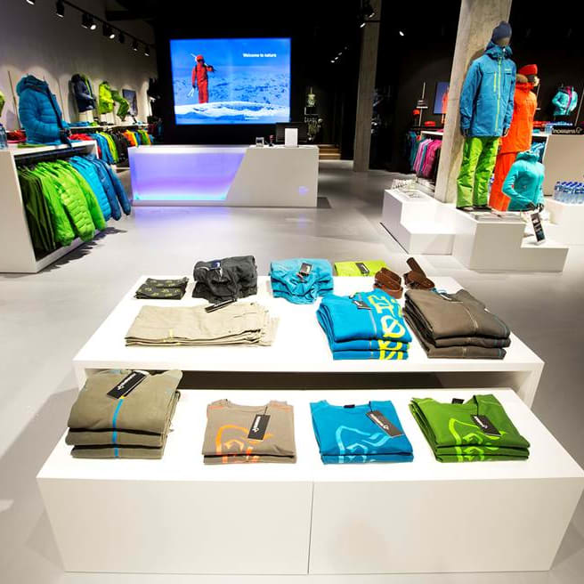 Inside a Norrøna store displaying colorful outdoor clothing on tables, racks, and mannequins.
