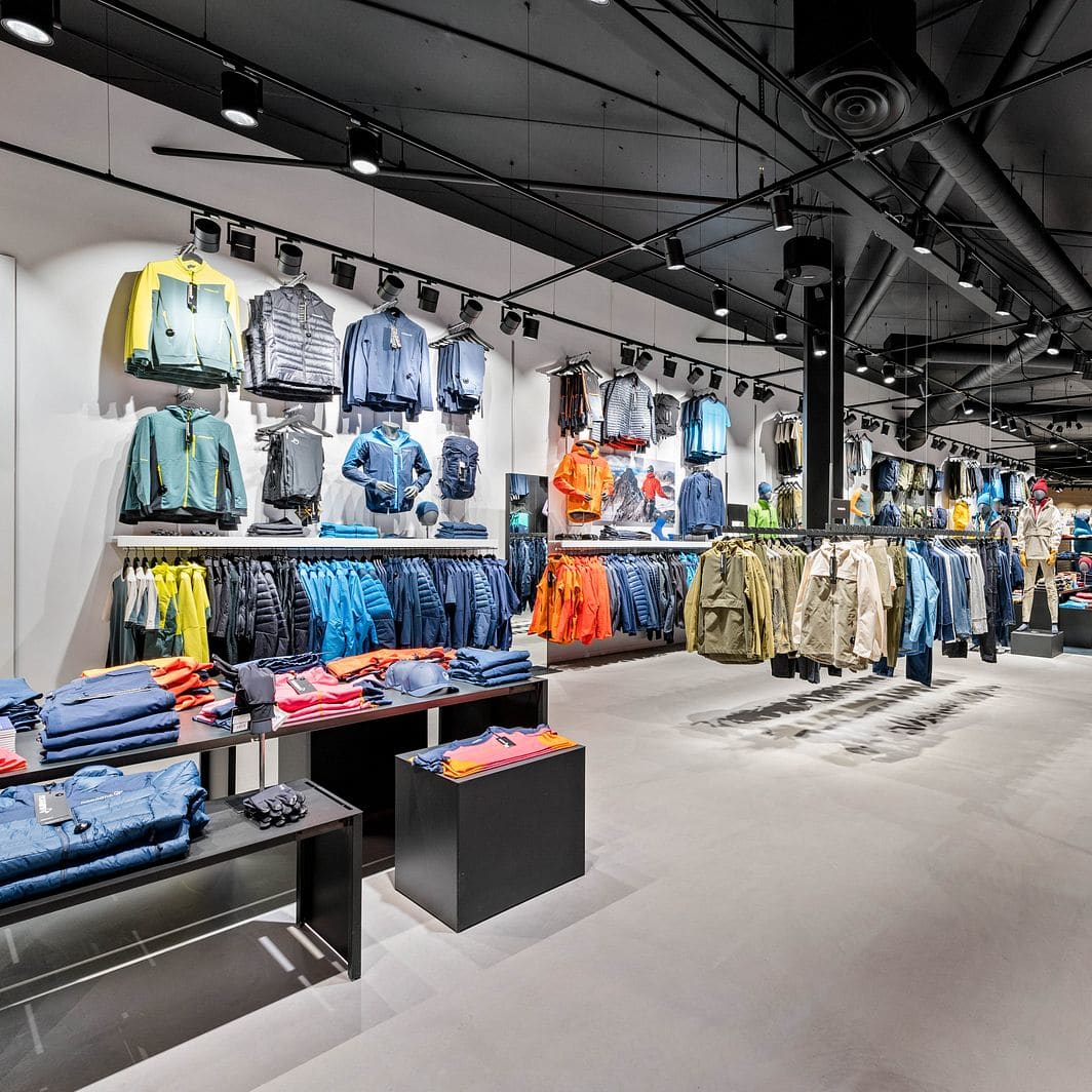 A modern Norrøna retail store displaying colorful outdoor clothing on racks and tables.