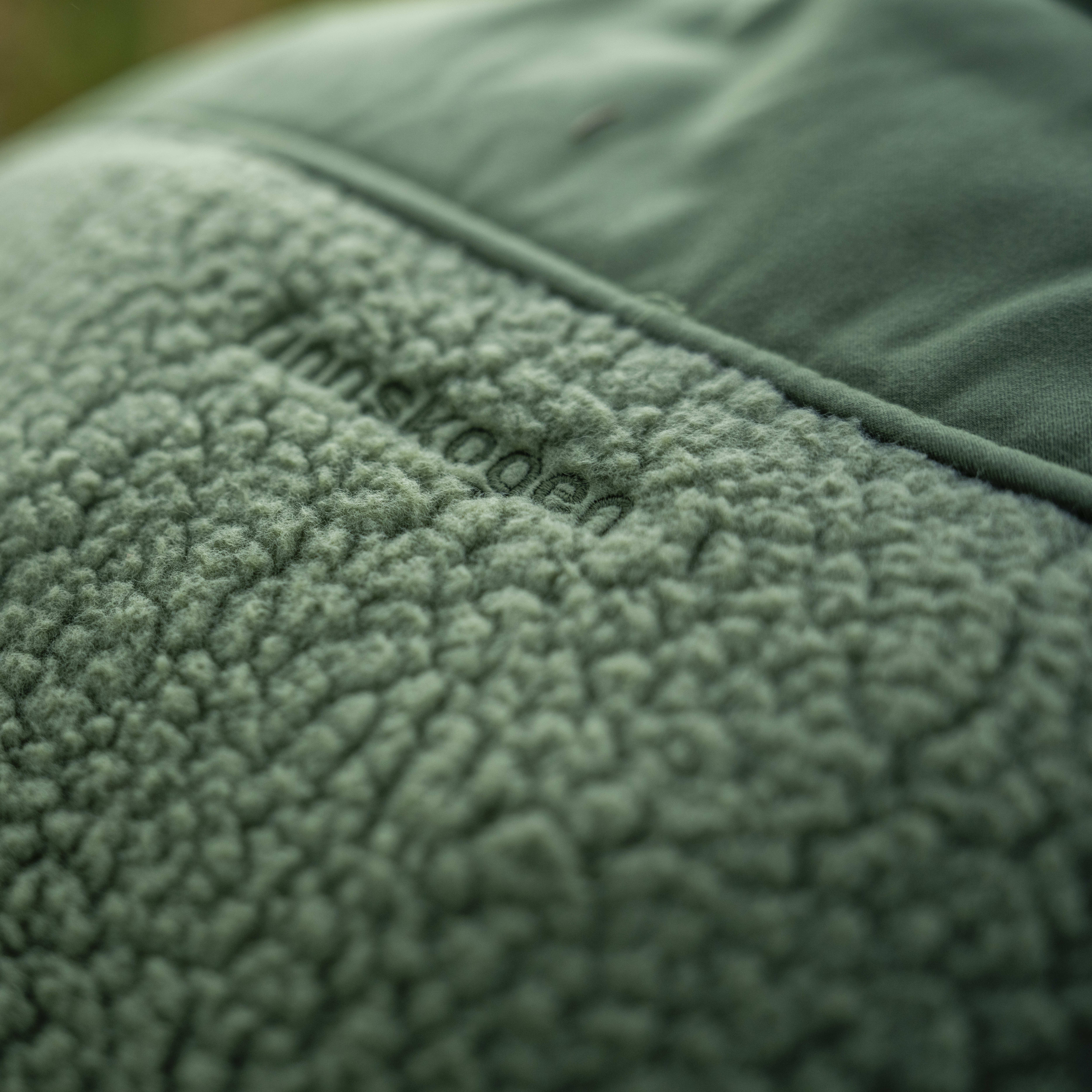Closeup of a green Norrøna fleece jacket. The fabric is soft and fluffy. 
