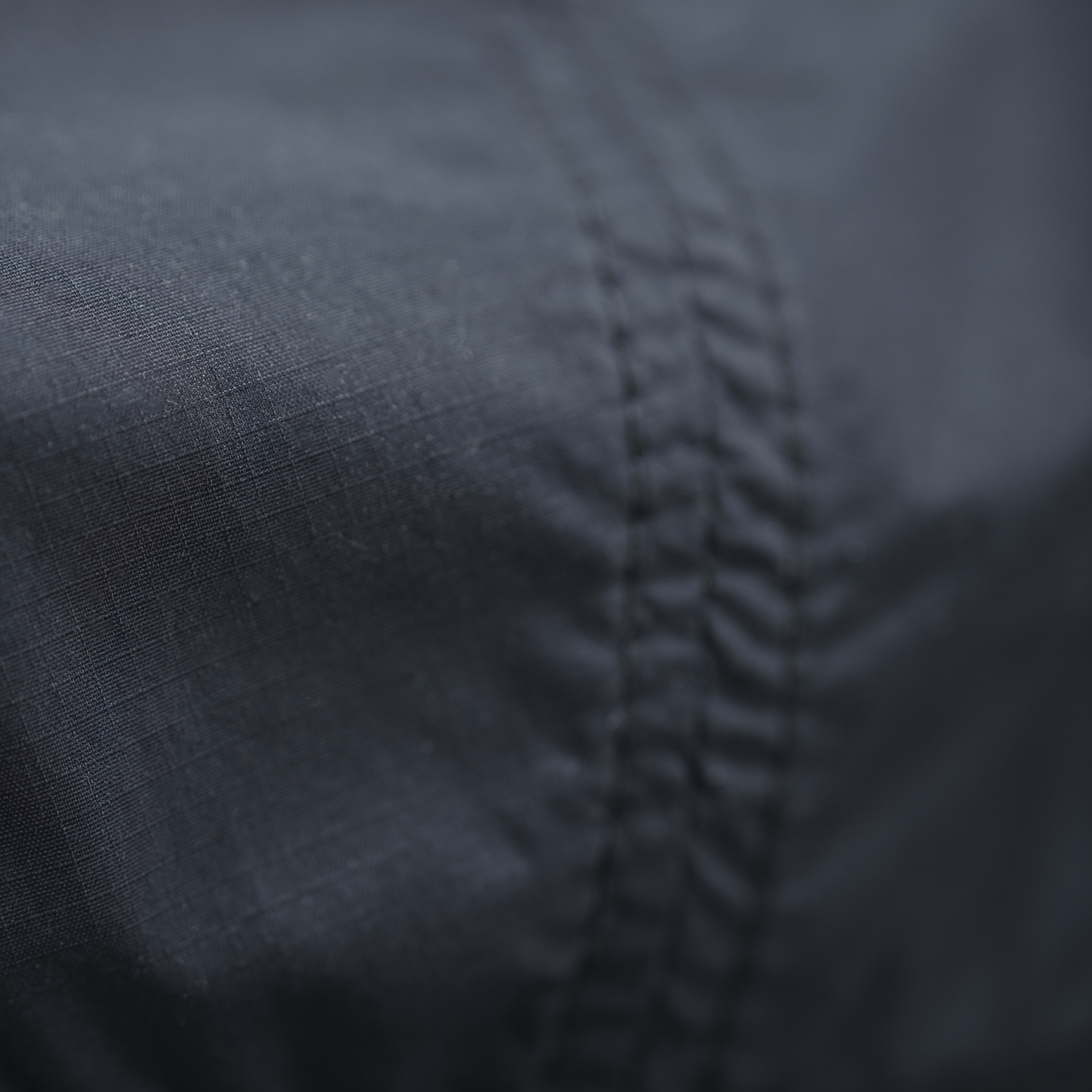 Close-up of dark blue Norrøna fabric with a seam running down the side. 

