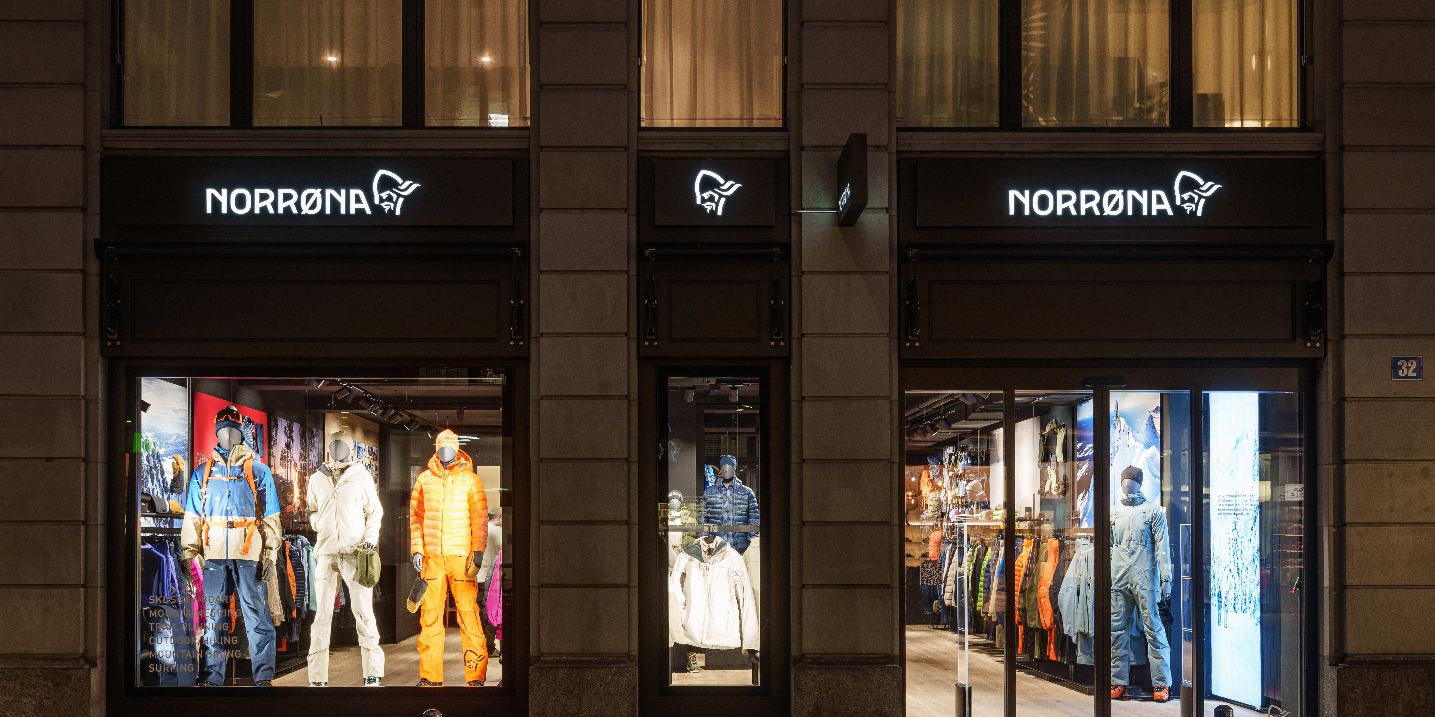 Storefront of Norrøna outdoor clothing brand featuring mannequins dressed in their apparel. Illuminated signage above each entrance.