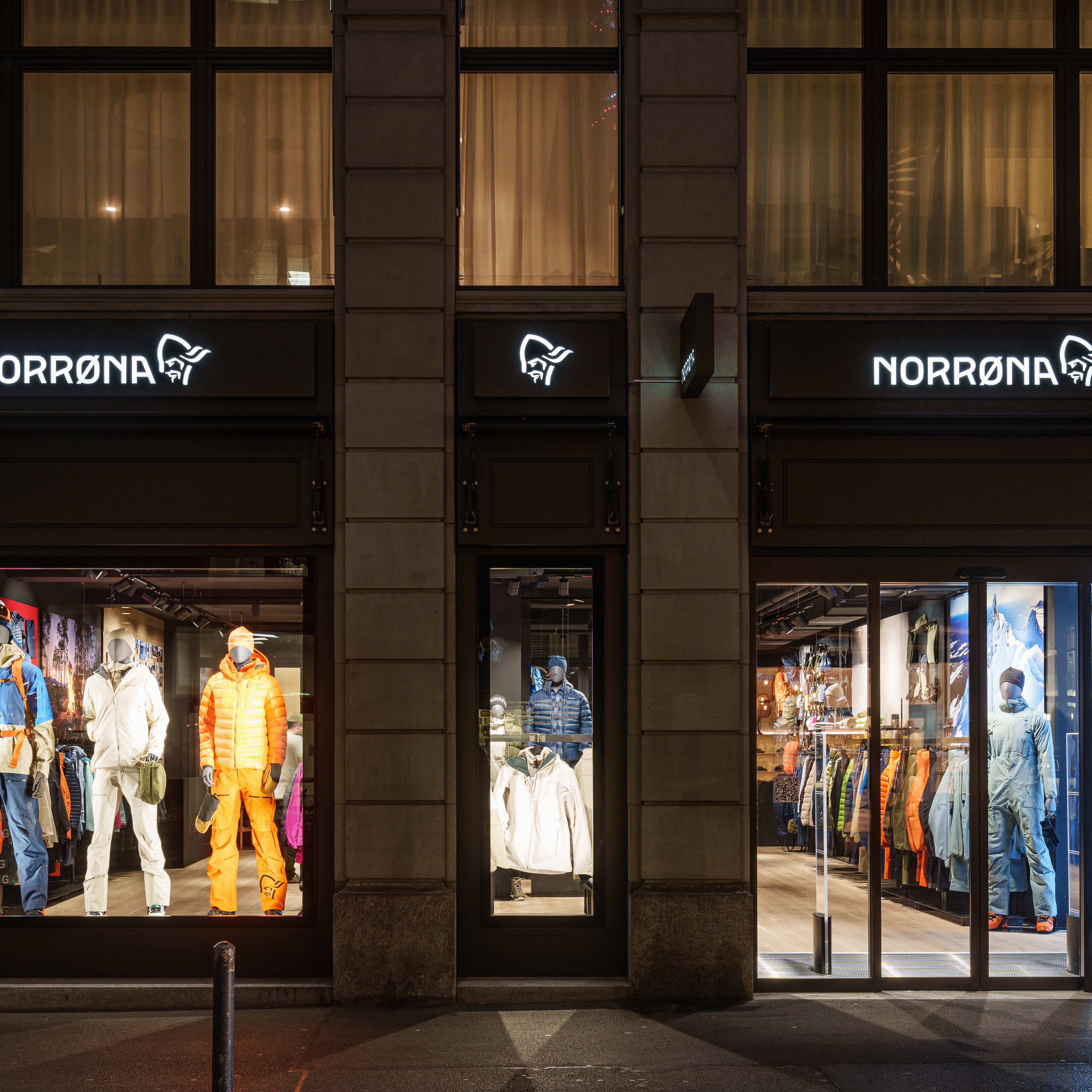 Storefront of Norrøna outdoor clothing brand featuring mannequins dressed in their apparel. Illuminated signage above each entrance.