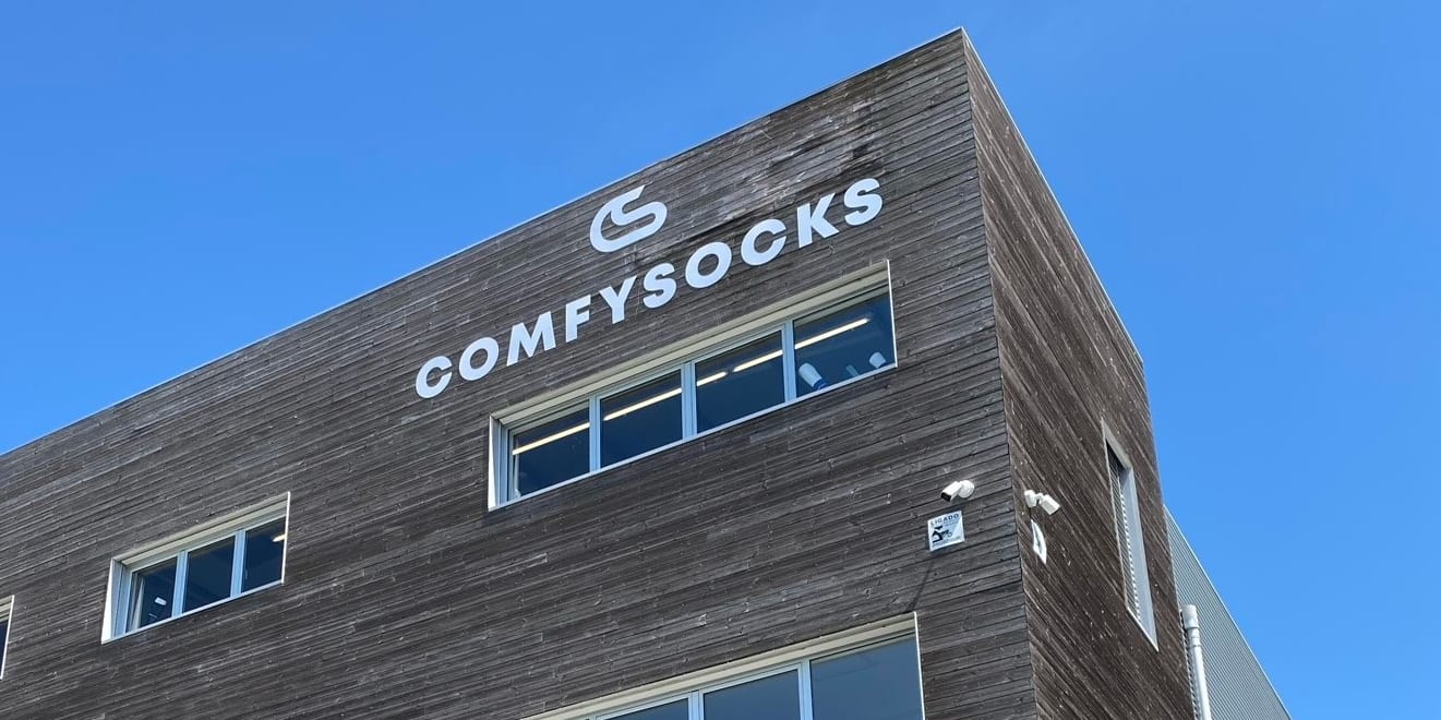 Exterior shot of the ComfySocks building, featuring a wooden facade, windows, and clear blue sky.