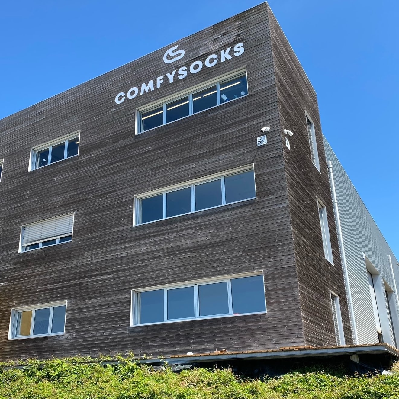 Exterior shot of the ComfySocks building, featuring a wooden facade, windows, and clear blue sky.