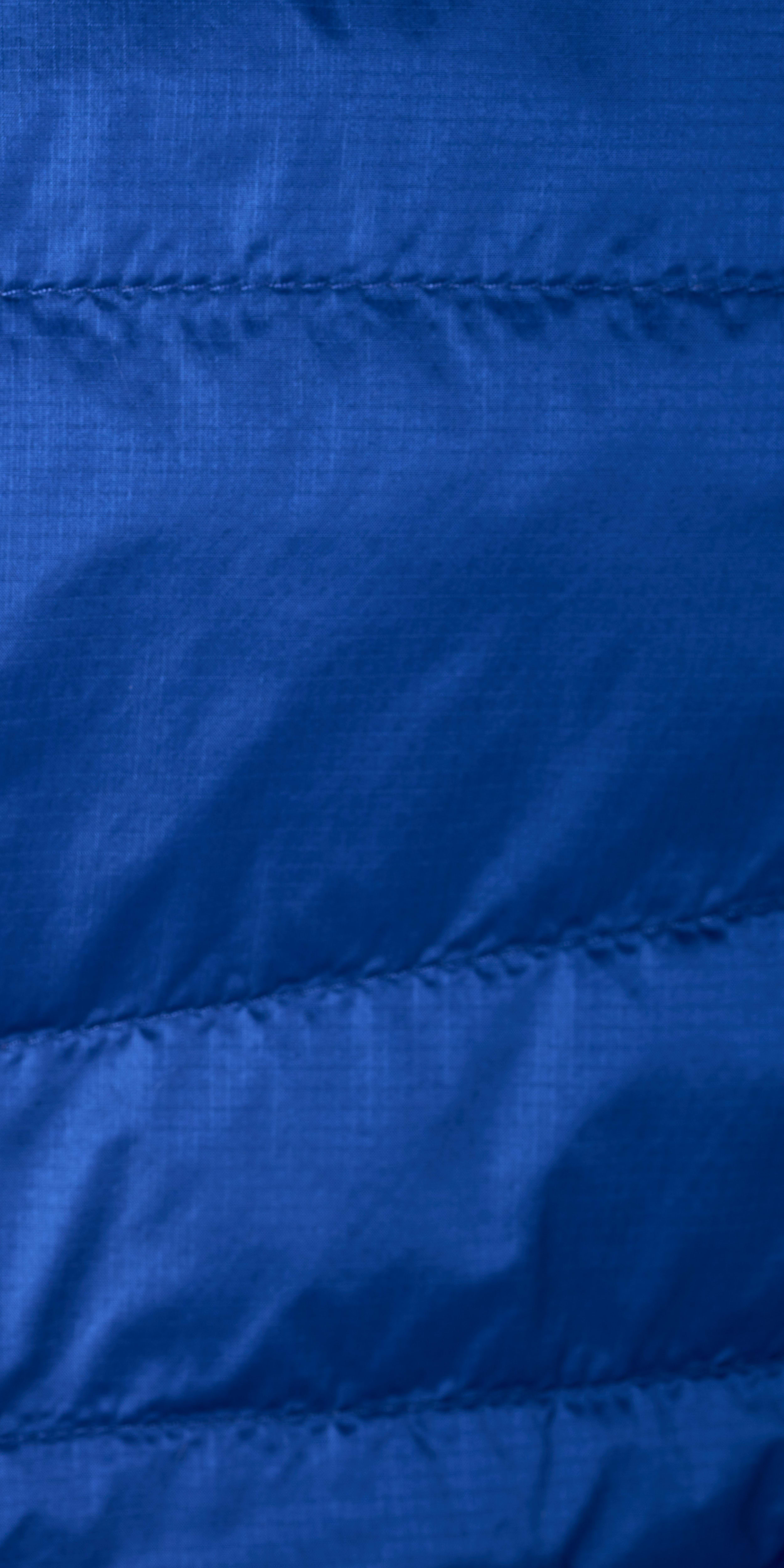 Close-up of blue Norrøna jacket fabric with horizontal stitching. 
