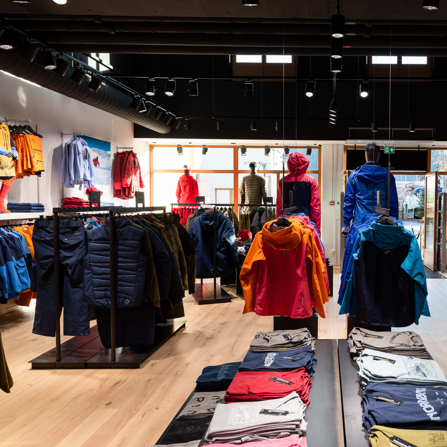 Norrøna outdoor jackets and apparel displayed in a brightly lit, modern retail store interior.