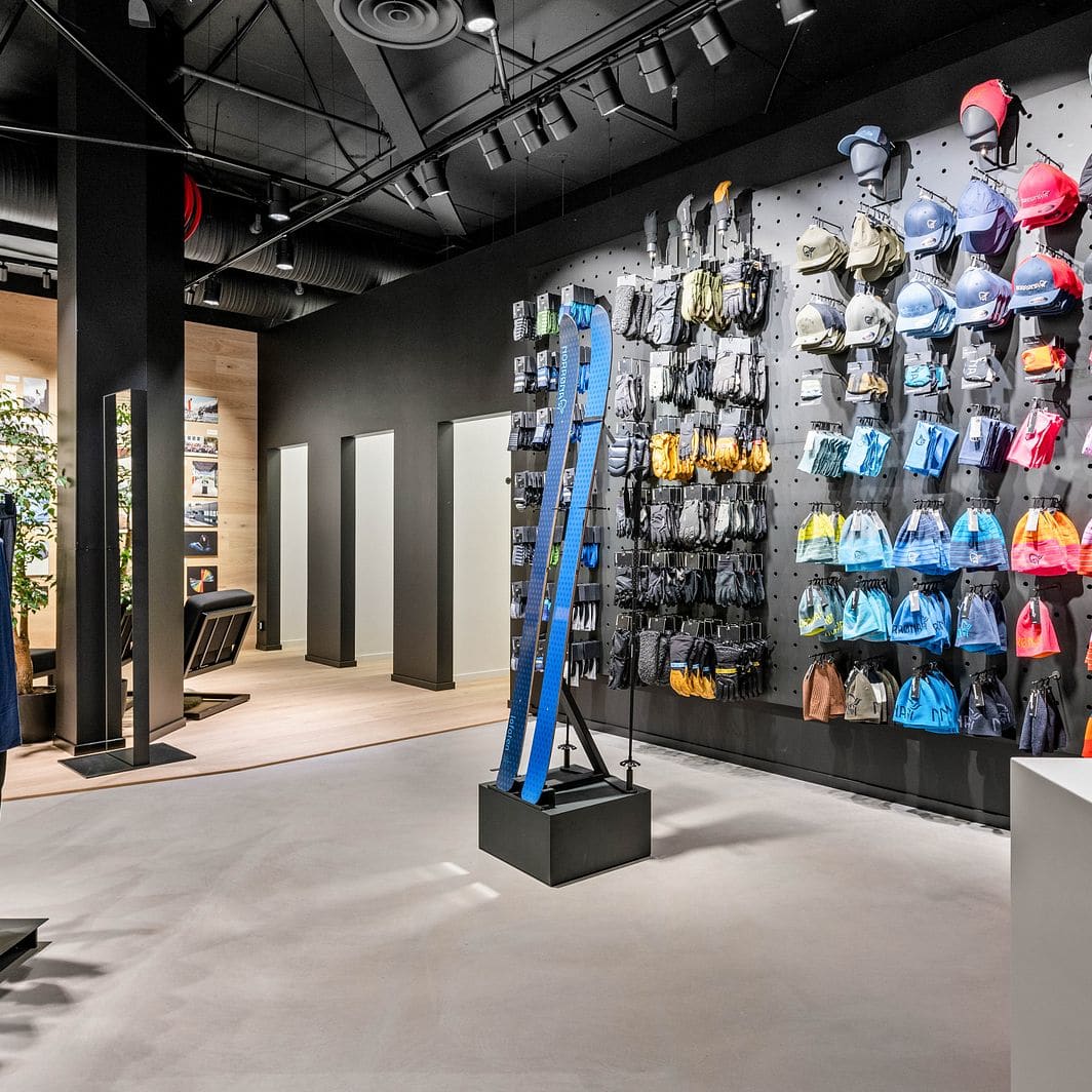 Norrøna store interior with a rack of Norrøna clothing, display skis, and a wall of hats and gloves.