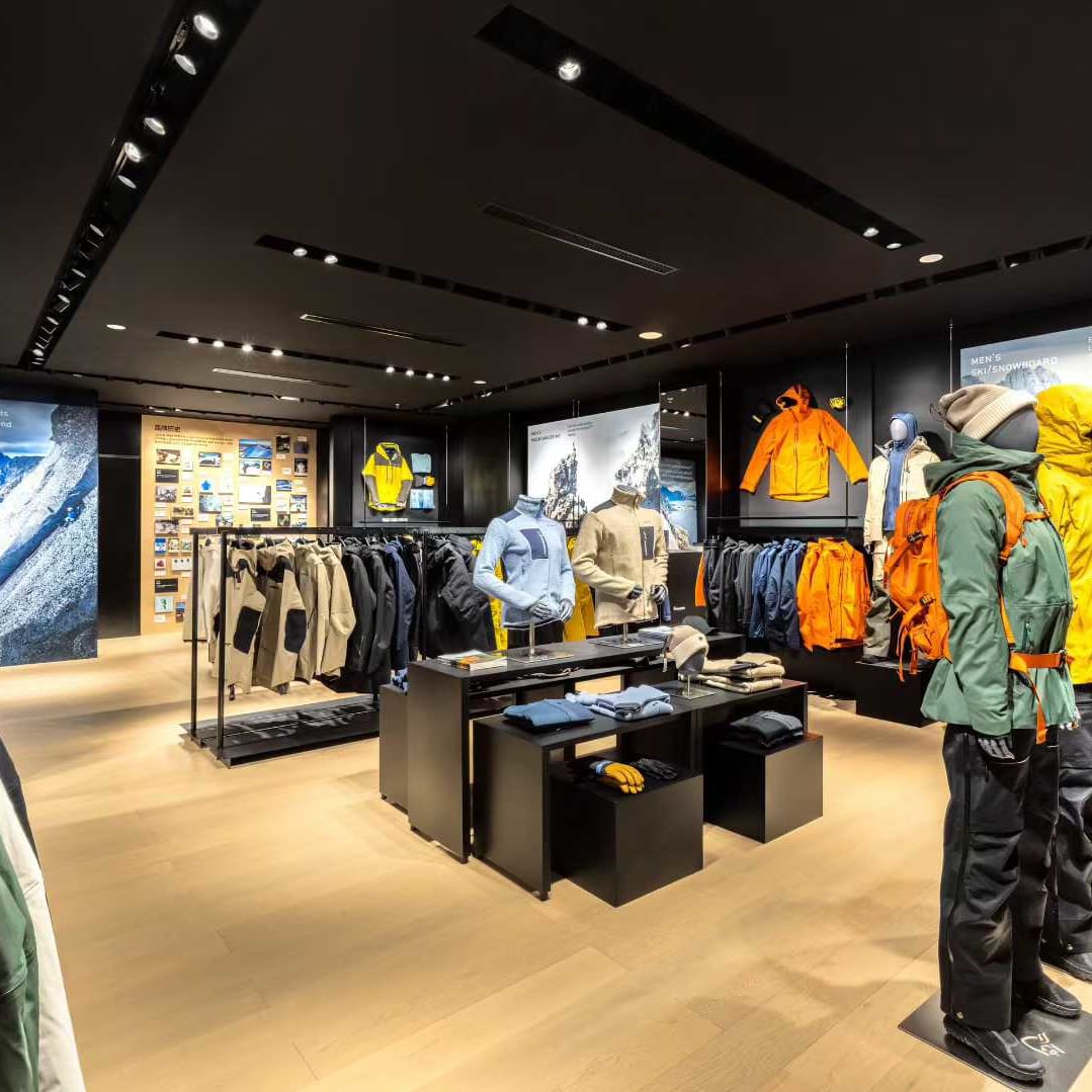 A retail store interior featuring Norrøna outdoor clothing displayed on mannequins and racks, with informational displays on the walls.