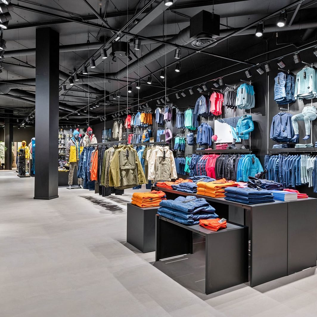 Interior of a modern Norrøna retail store showcasing colorful outdoor clothing on racks and display tables.