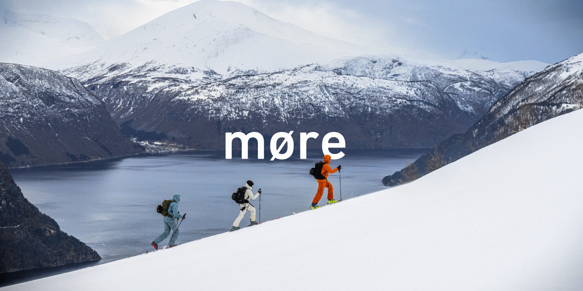 Three skiers in Norrøna outerwear ascend a snowy slope above a fjord. Text overlay: "møre".